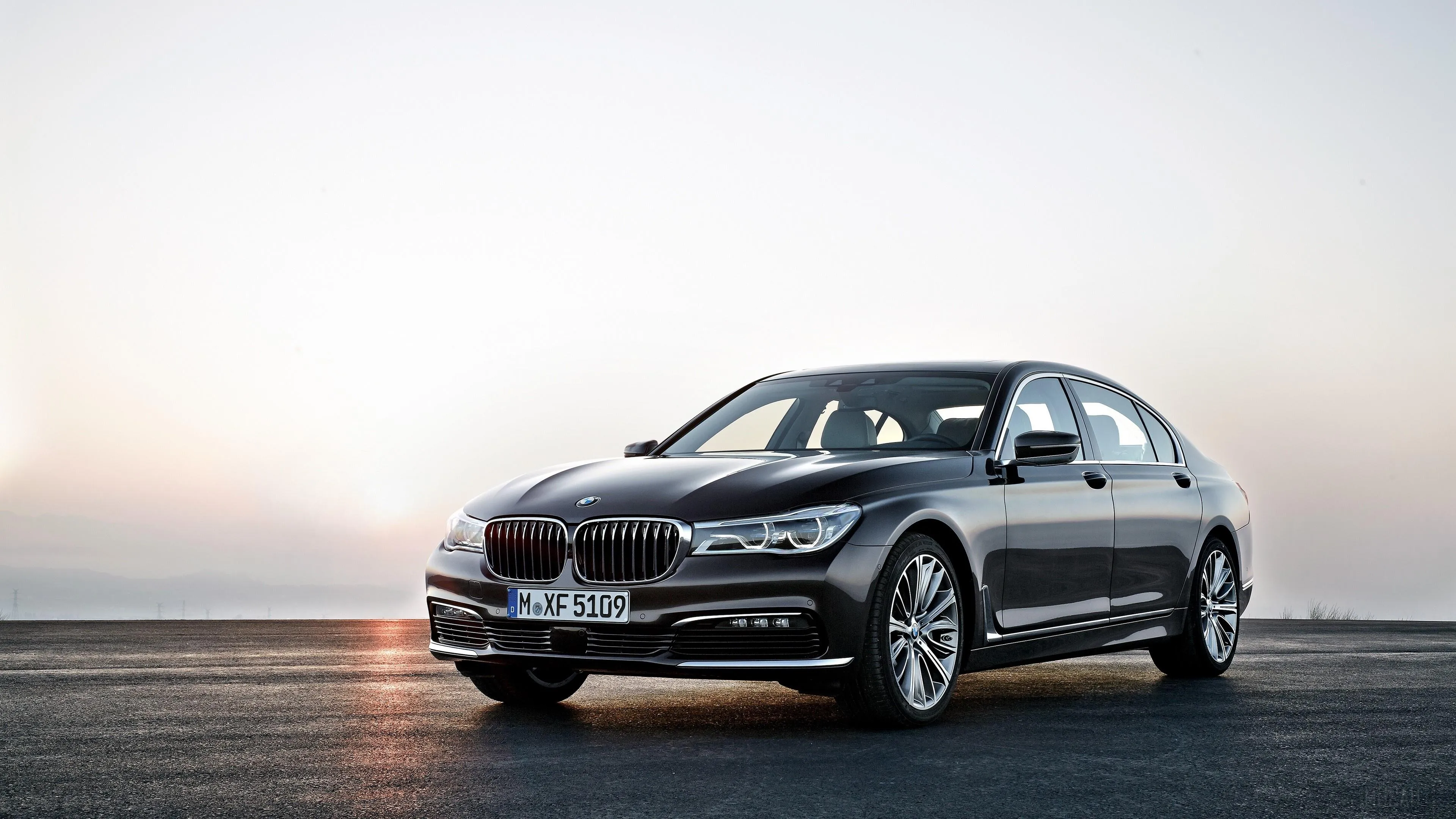 Bmw Sedan Under Sunset Lighting on Open Road Wallpaper
