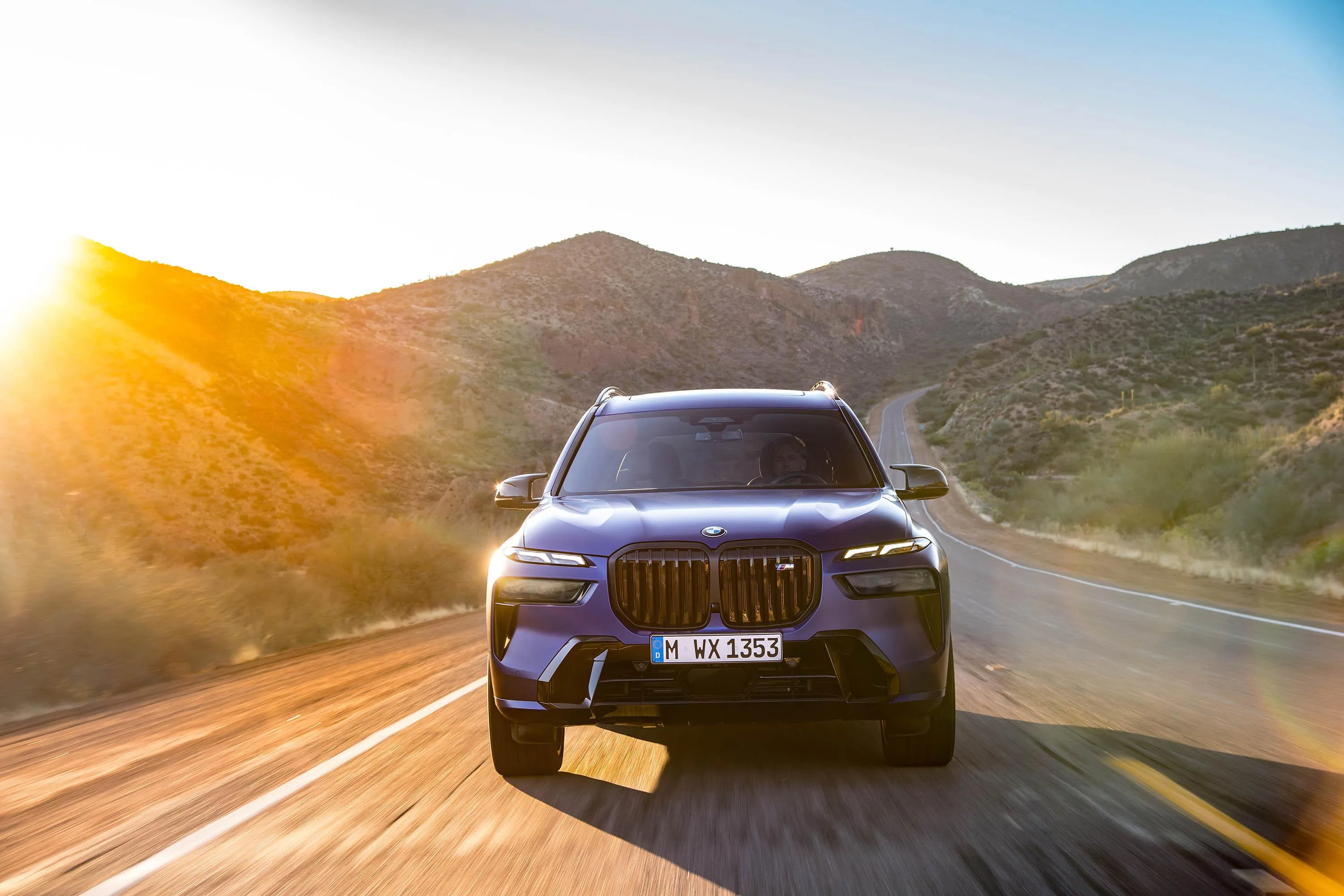 Bmw Suv Driving Into Bright Sunset on Hill Road Wallpaper