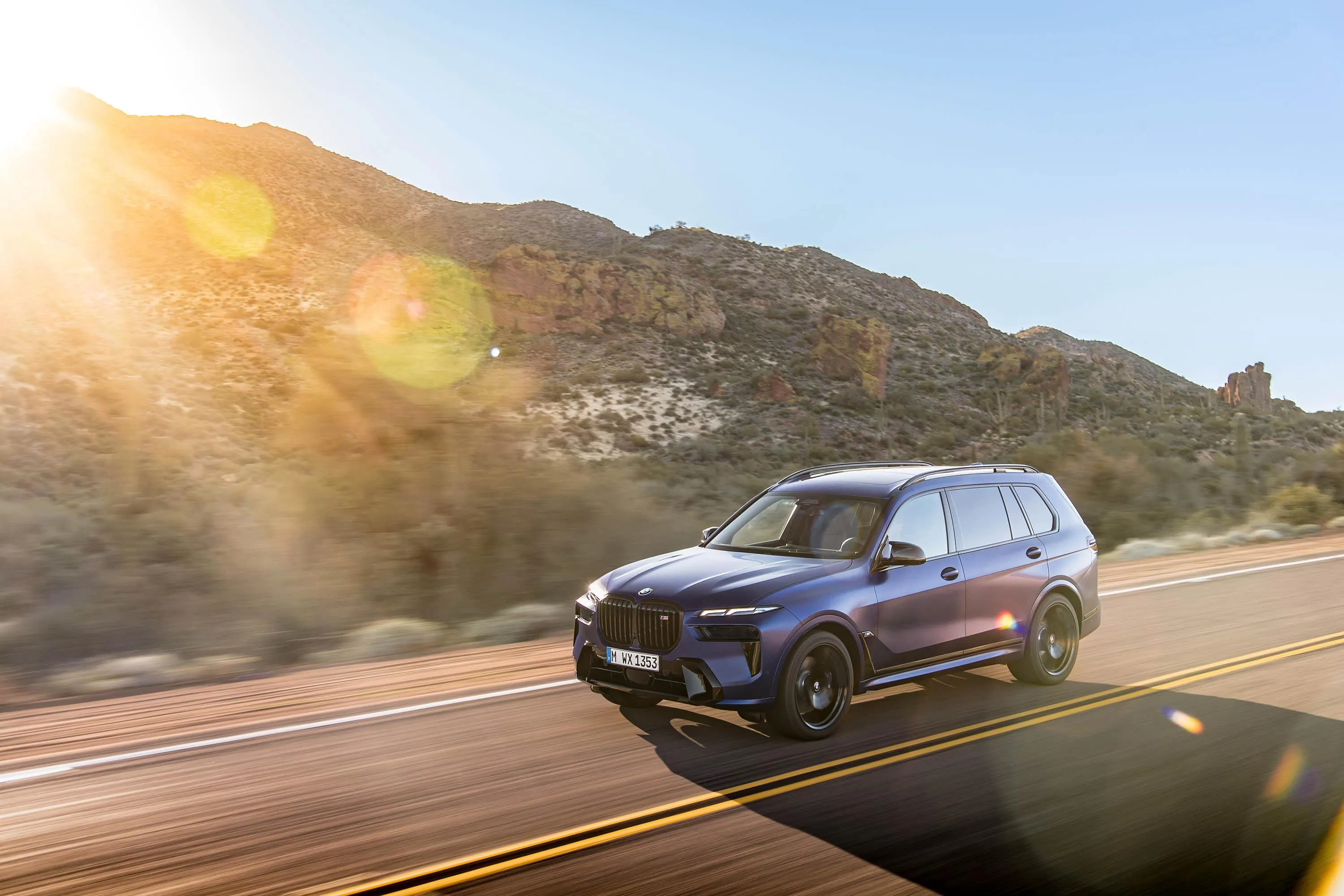 Bmw Suv Driving Into Sunlight on Desert Highway Image