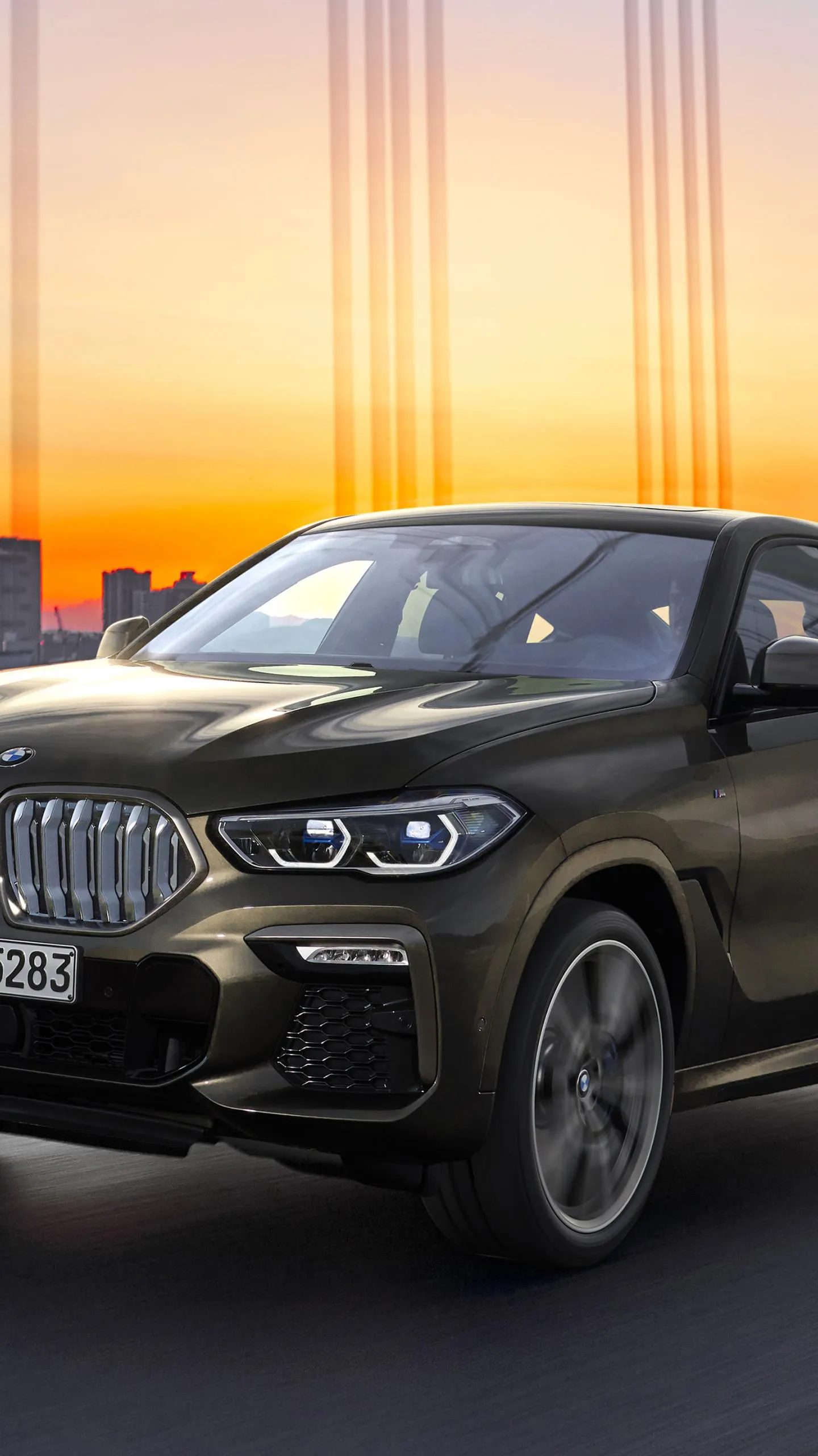 Bmw Suv Driving Into Sunset Light in Urban Area Wallpaper