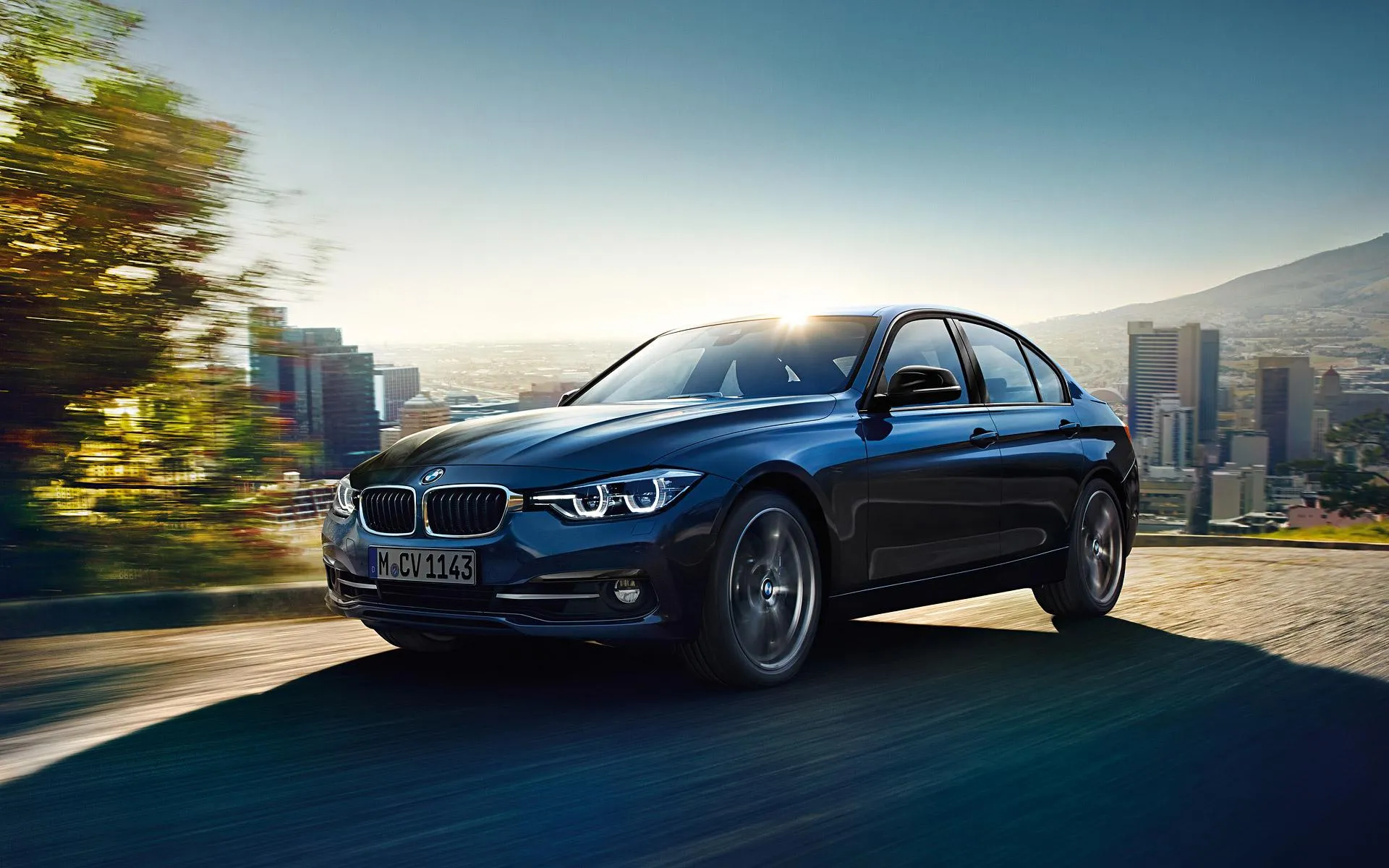 Bmw Suv Driving on a Mountain Road with City View Wallpaper