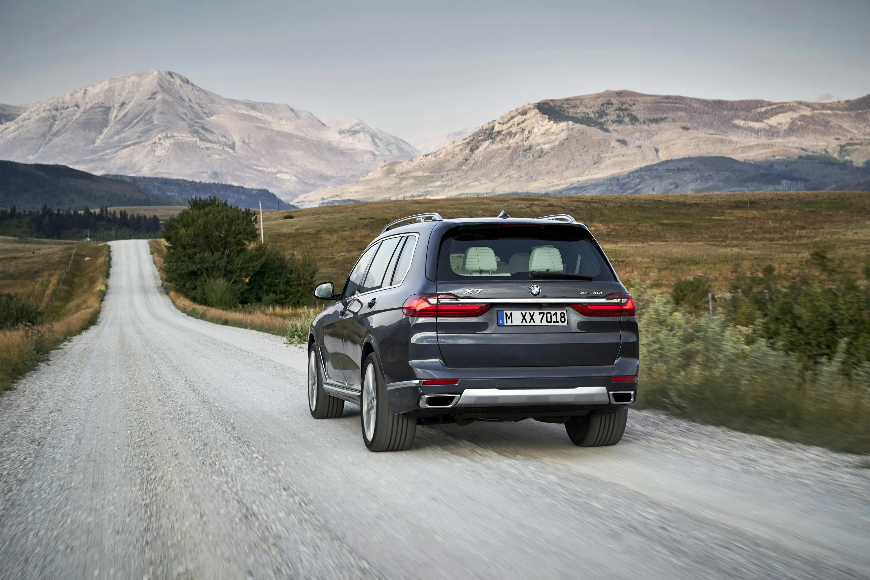 Bmw Suv Driving on Dusty Road with Mountains Behind