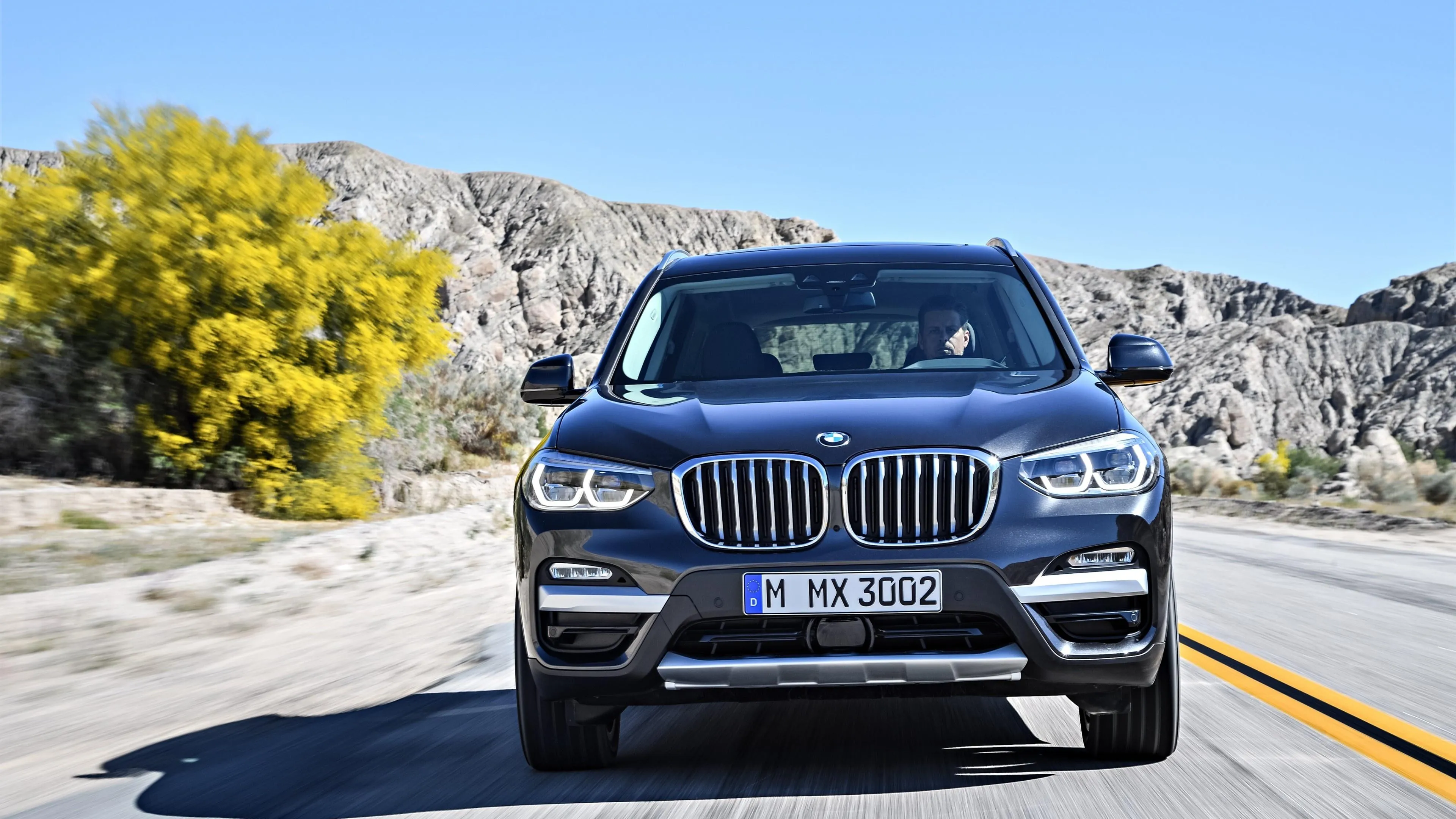 Bmw Suv Driving on Open Road with Blue Sky View Wallpaper