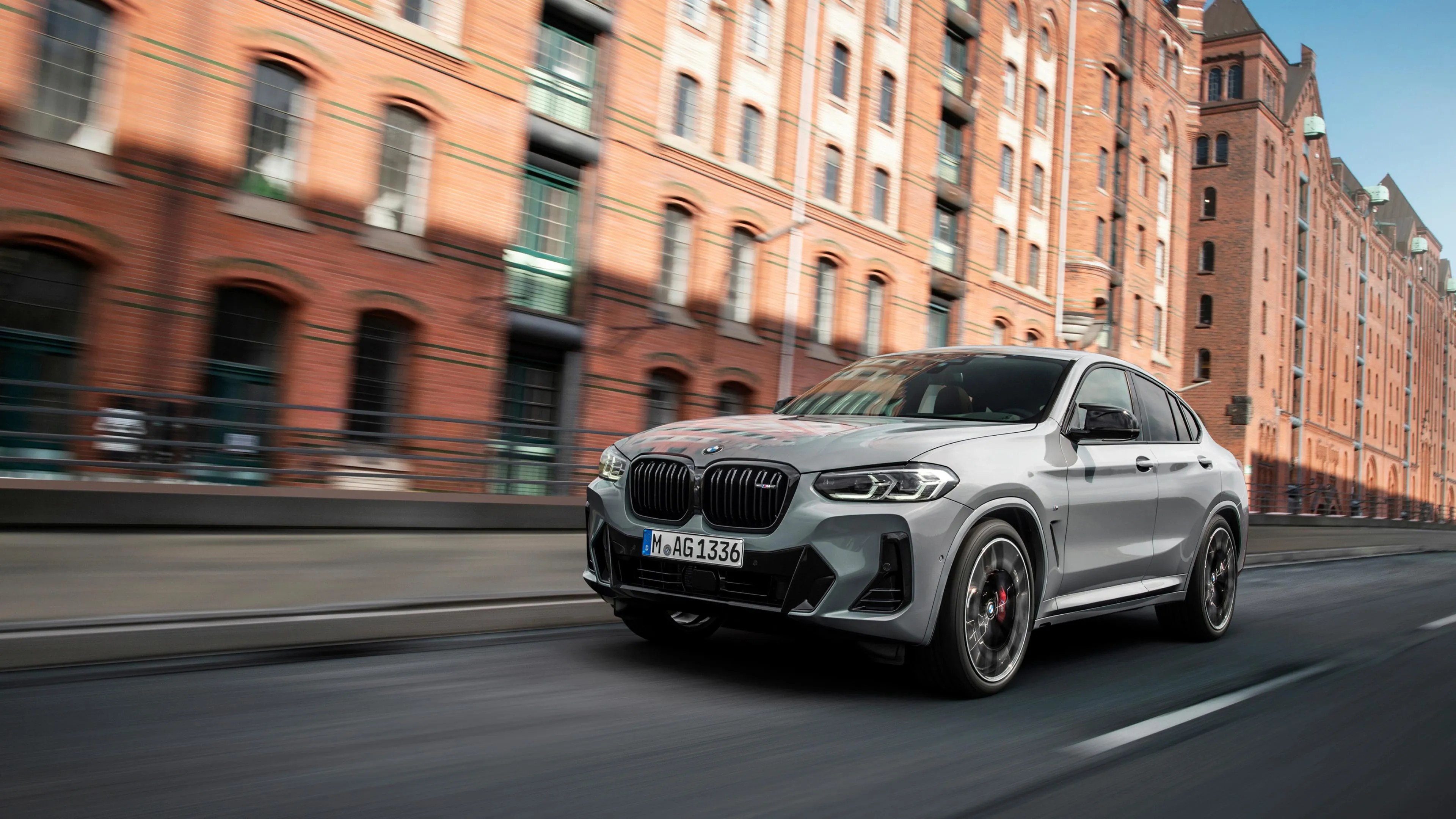Bmw Suv Driving Past Red Brick Buildings in the City