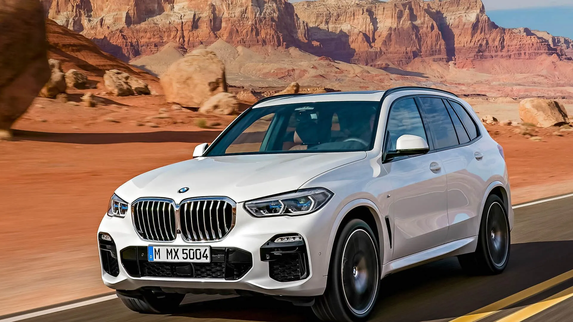 Bmw Suv Driving Through Desert Highway Near Red Cliffs
