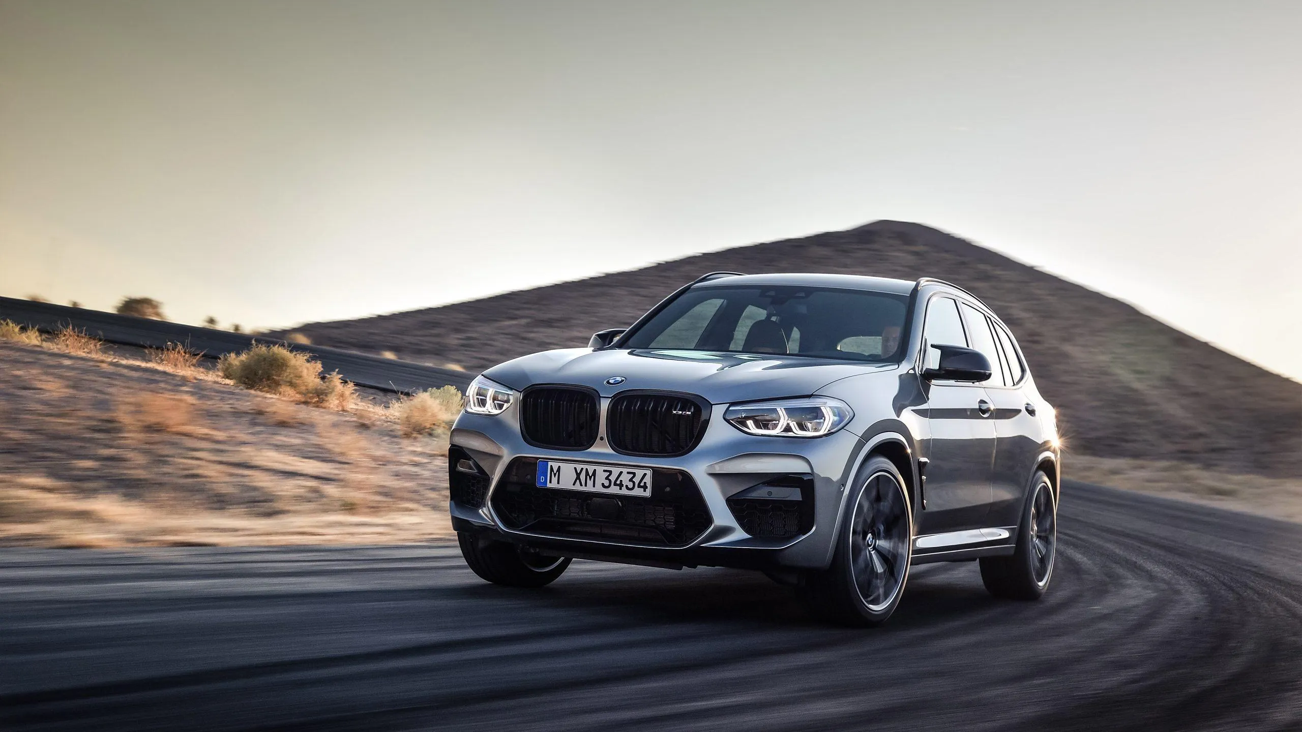 Bmw Suv Driving Through Desert Terrain at Sunset Wallpaper