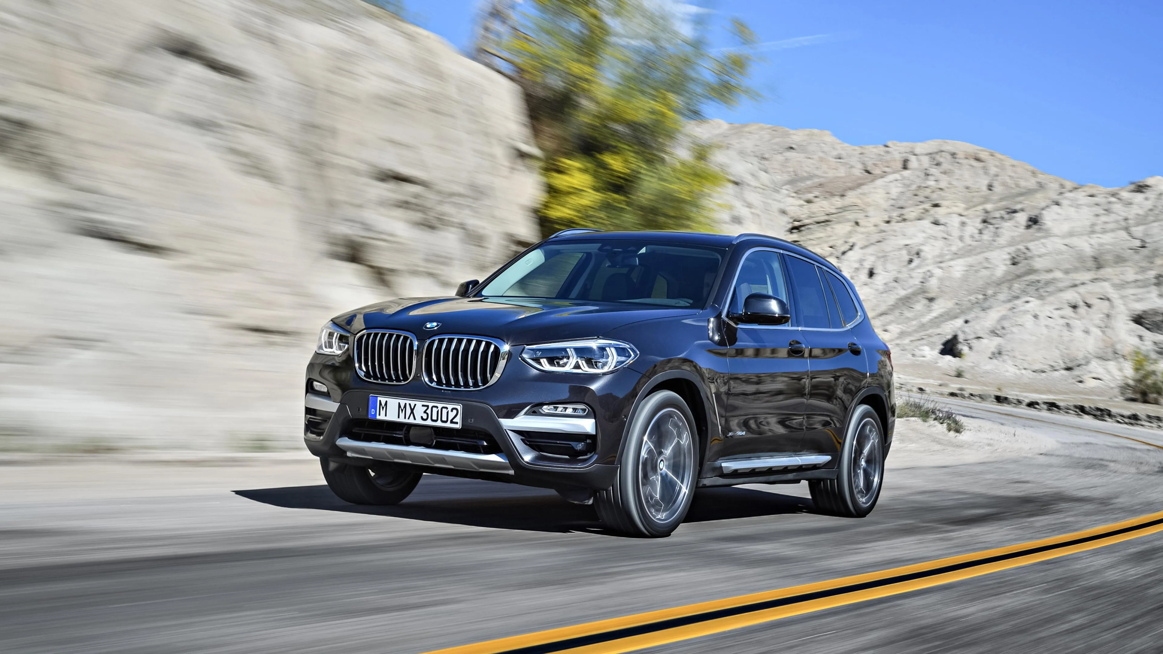 Bmw Suv Driving Through Mountain Road in Bright Sunlight
