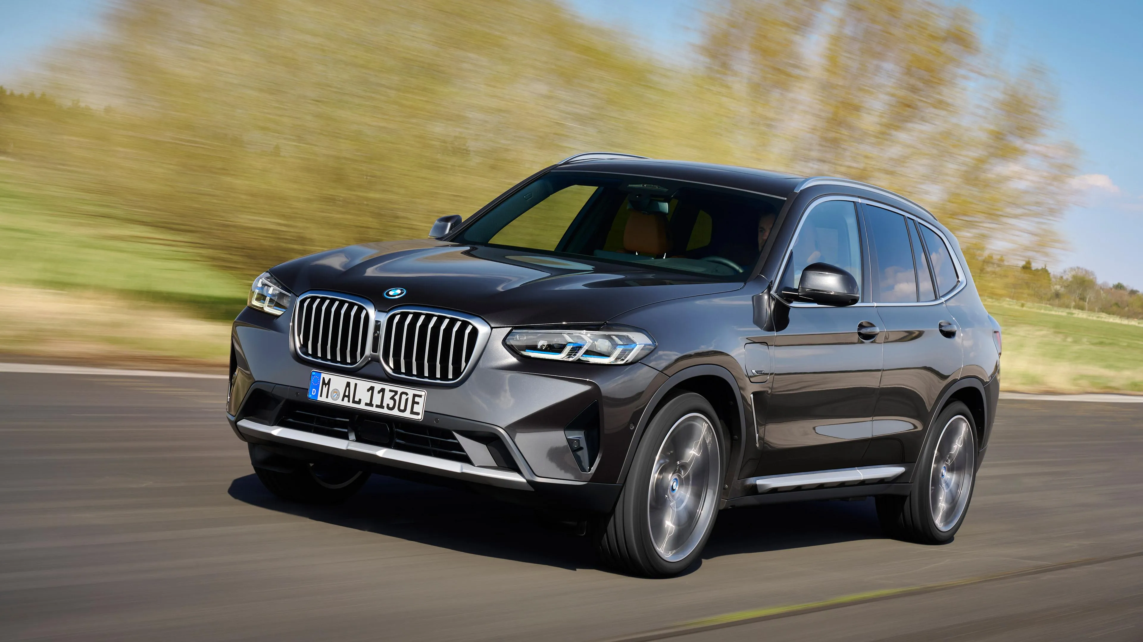 Bmw Suv in Motion on Countryside Road with Trees in Background
