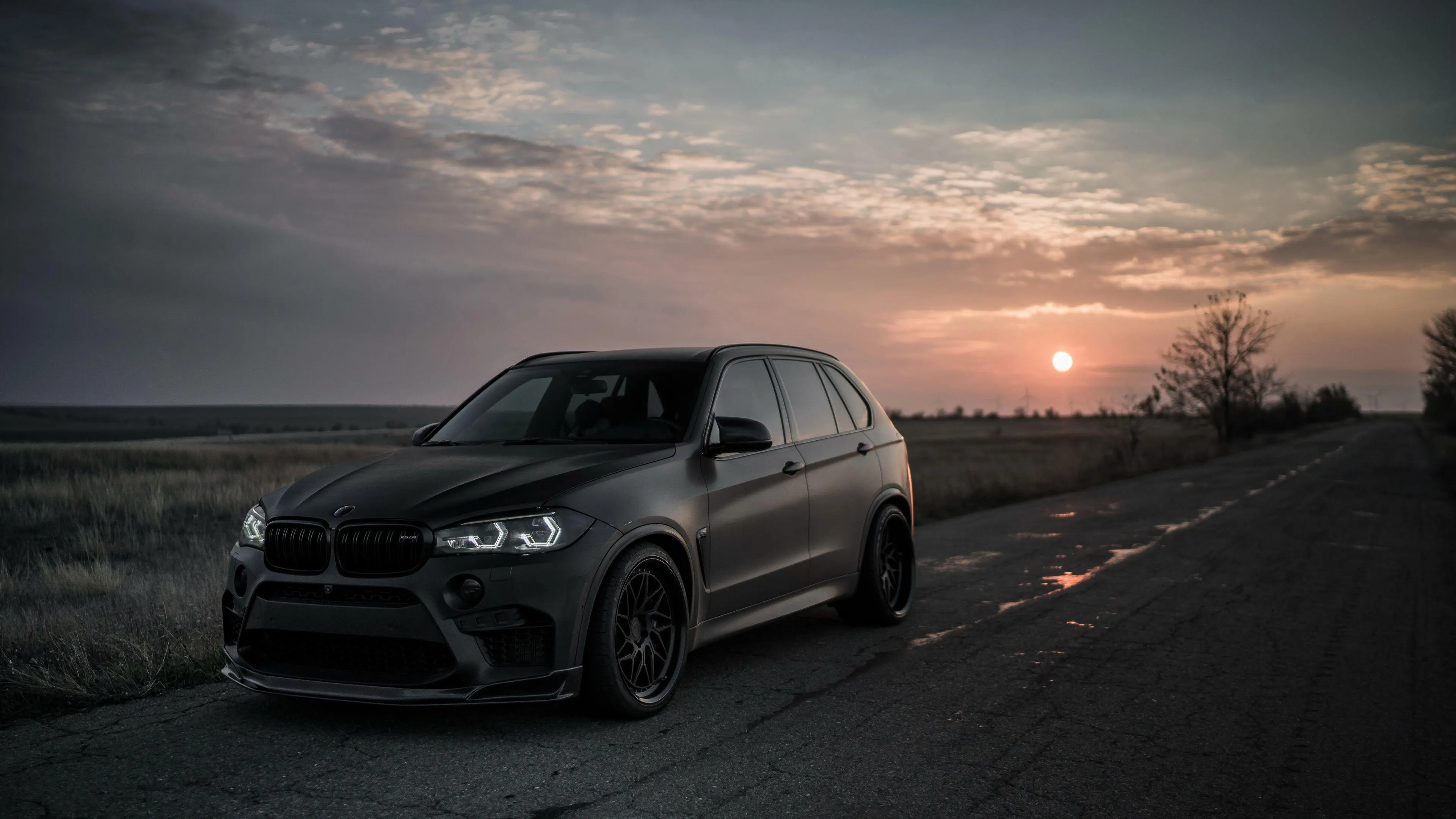 Bmw Suv on Dark Road at Sunset with Cloudy Sky Image
