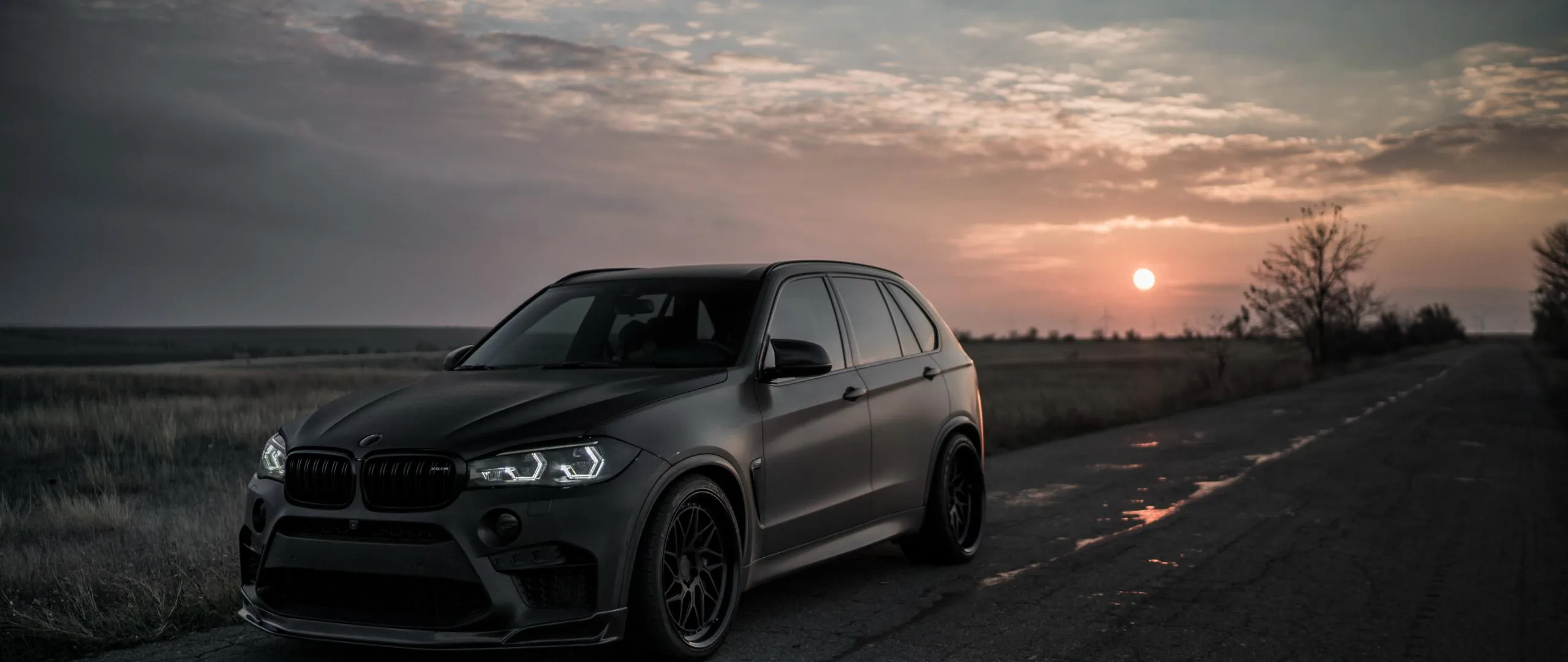 Bmw Suv on Road at Dusk with Dramatic Sky in the Background