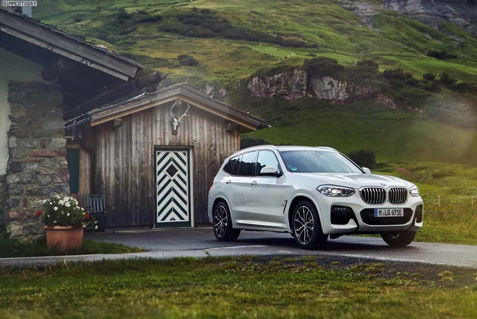 Bmw Suv Parked Beside a Cabin in a Green Hilly Area