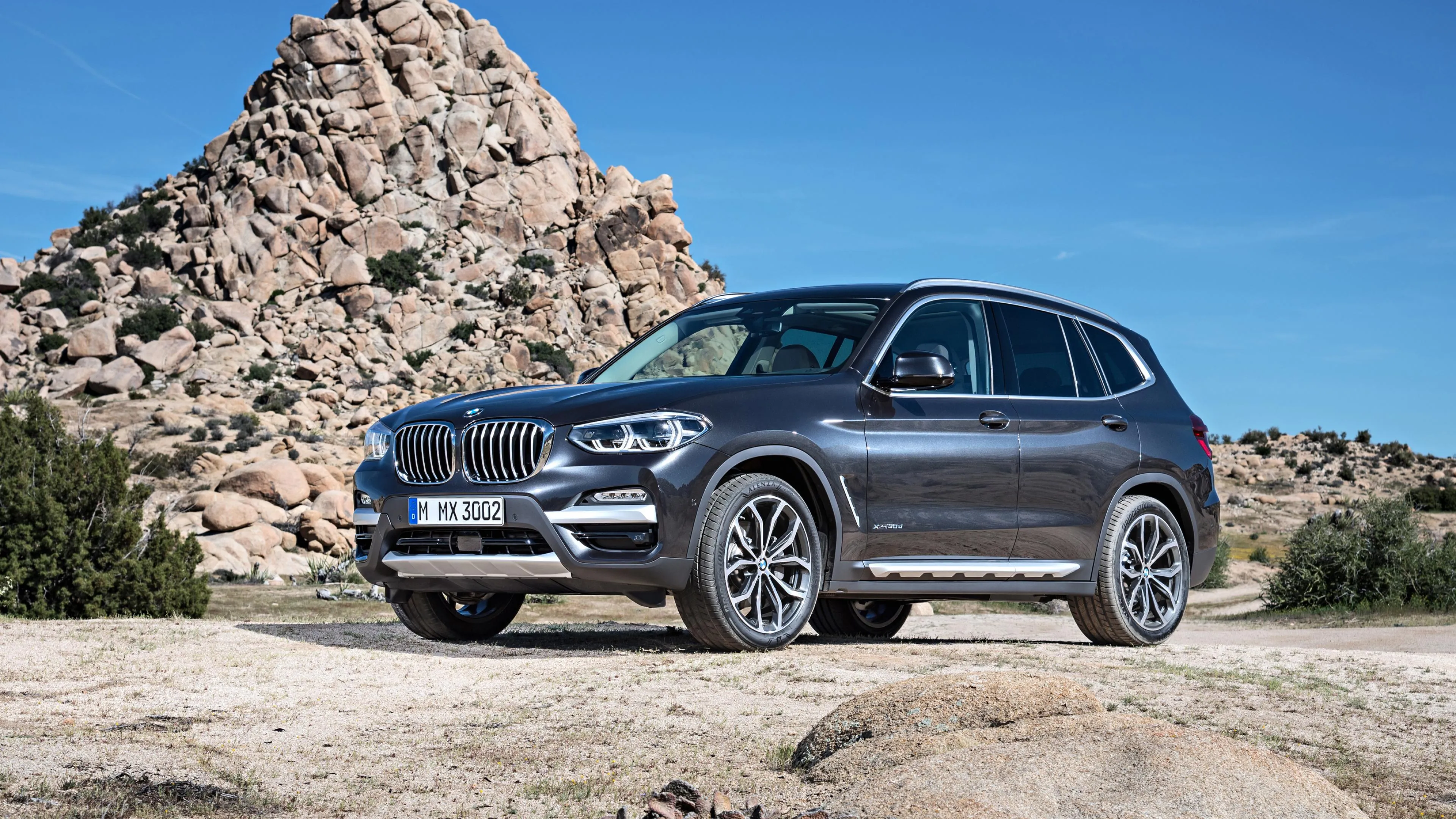 Bmw Suv Parked Beside Rocky Hill Under Bright Daylight