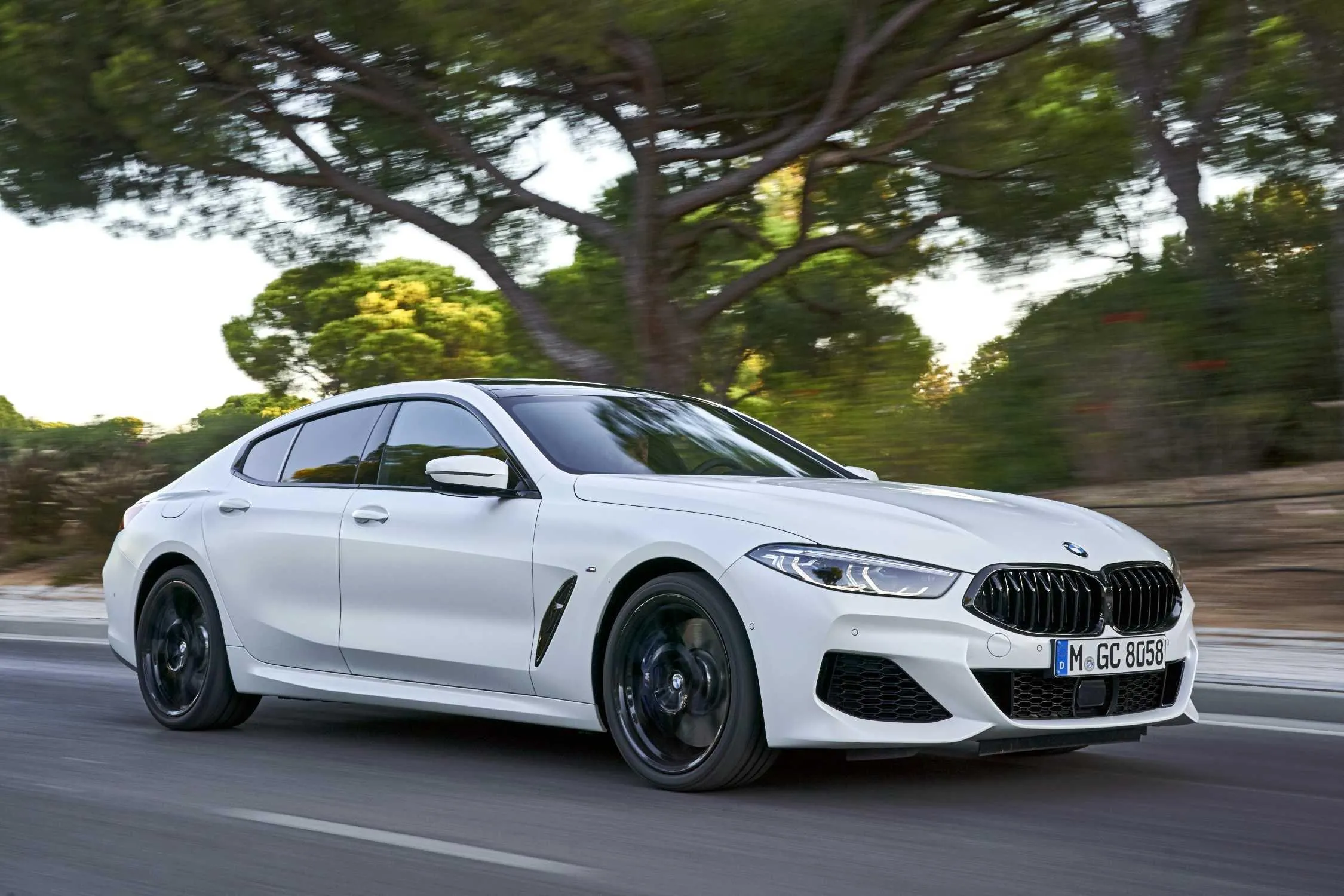 Bmw White Sports Car Driving on Tree Lined Road Wallpaper