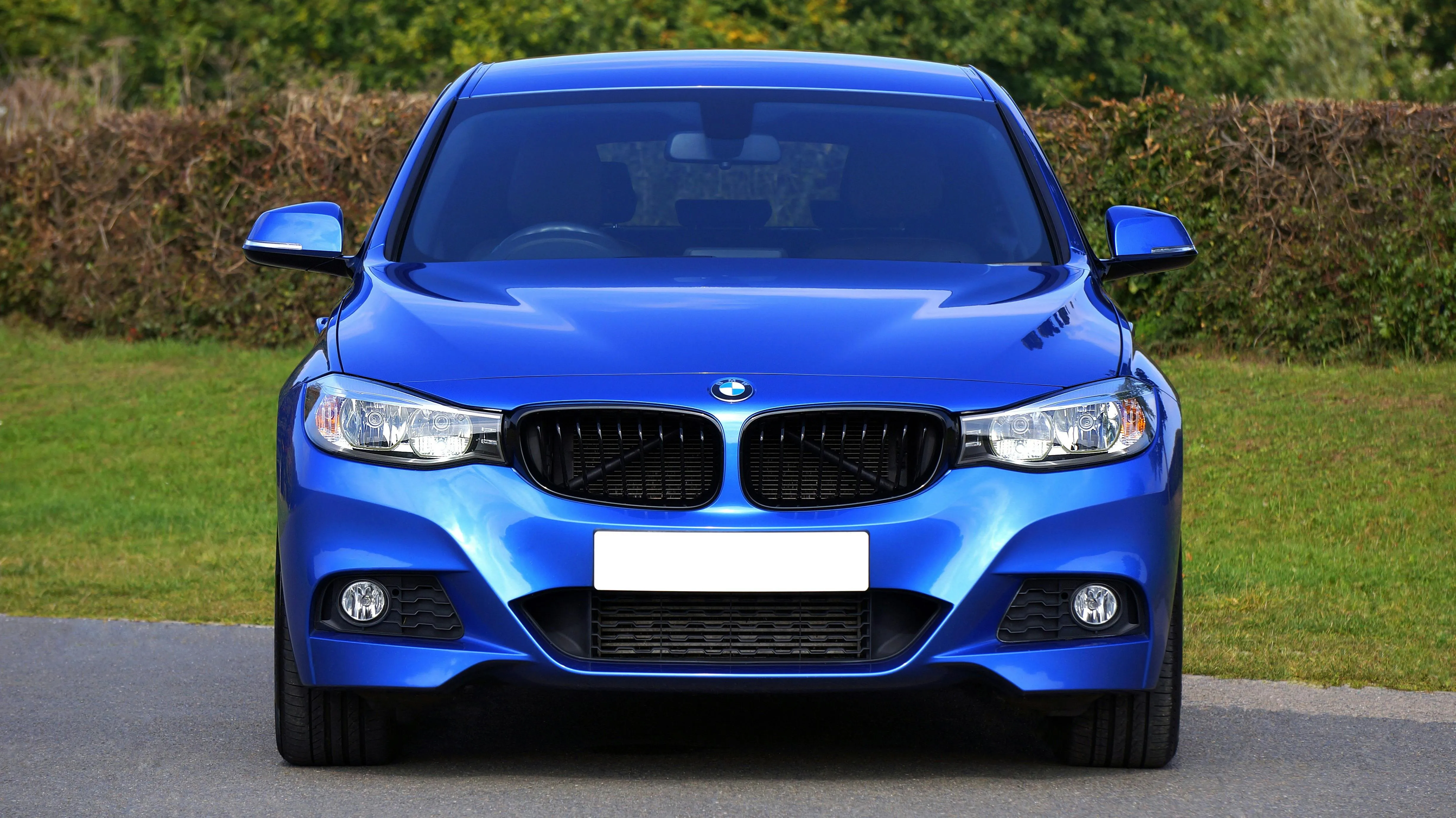 Bright Blue Bmw Parked on Road with Trees in Background