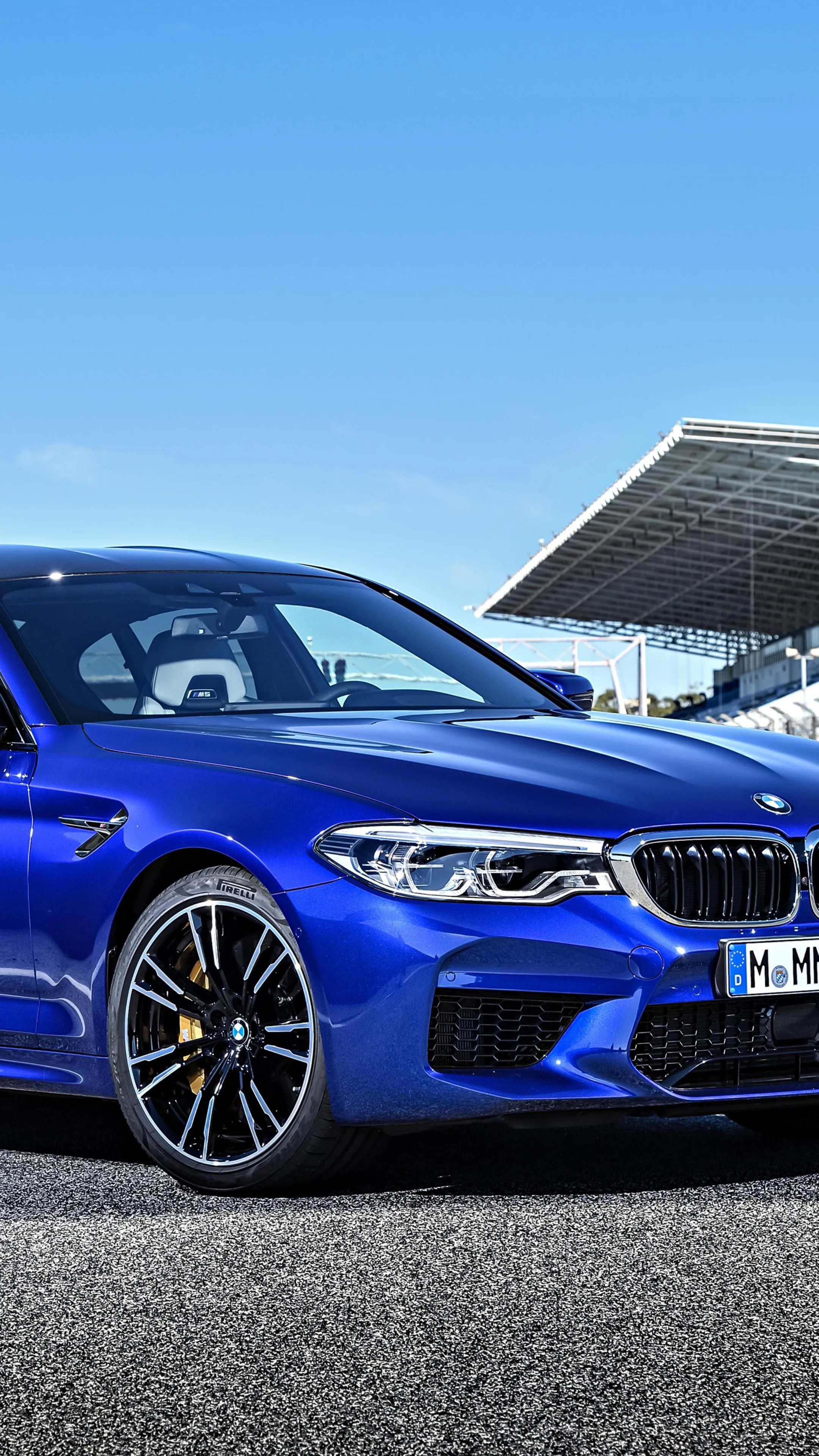 Bright Blue Bmw Sedan Parked Beside Modern Racetrack