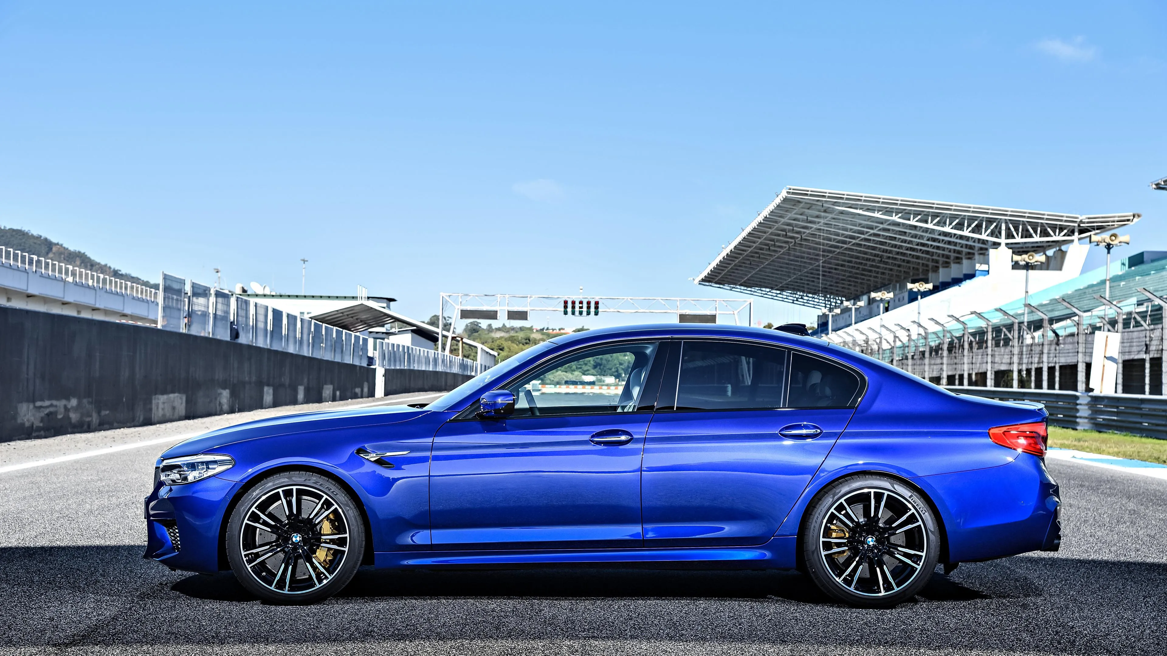 Bright Blue Bmw Sedan Parked Near Race Track Stands