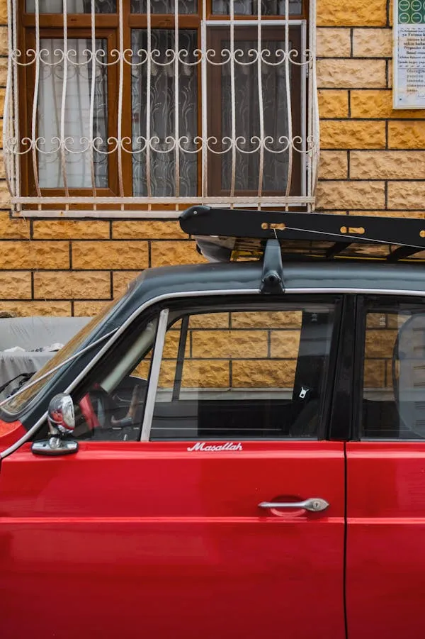 Bright Red Vintage Car With Roof Rack Near Window Wallpaper