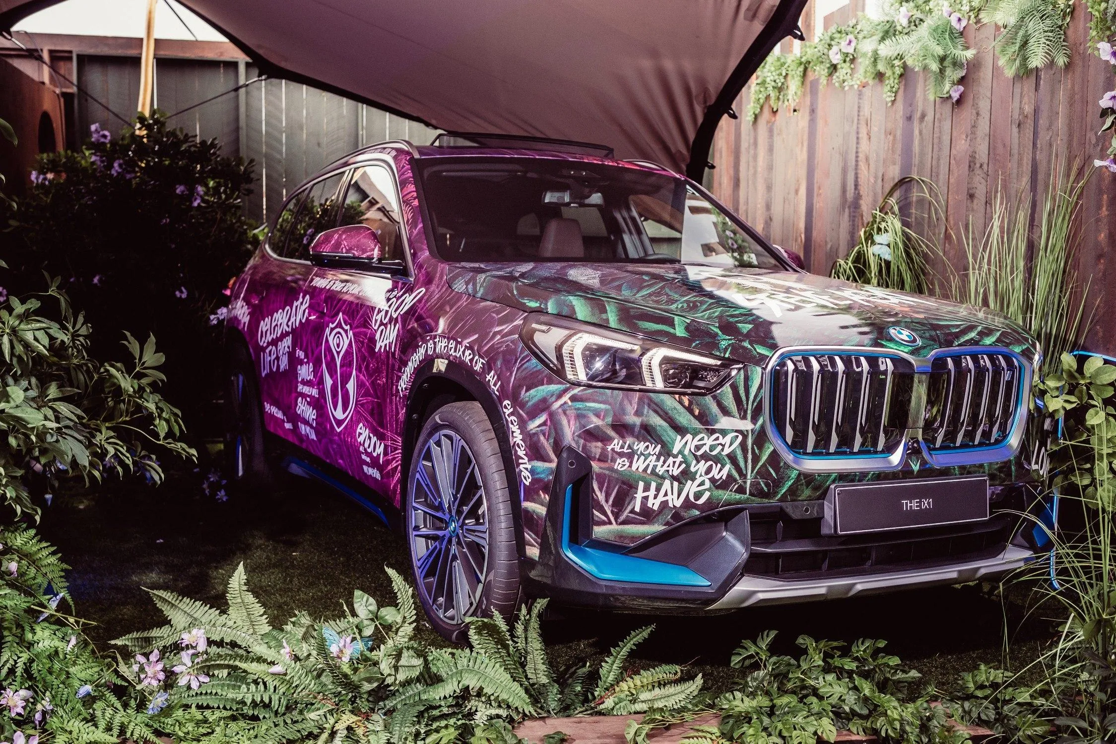 Camouflaged Bmw Suv Parked Near Wooden Fence and Plants