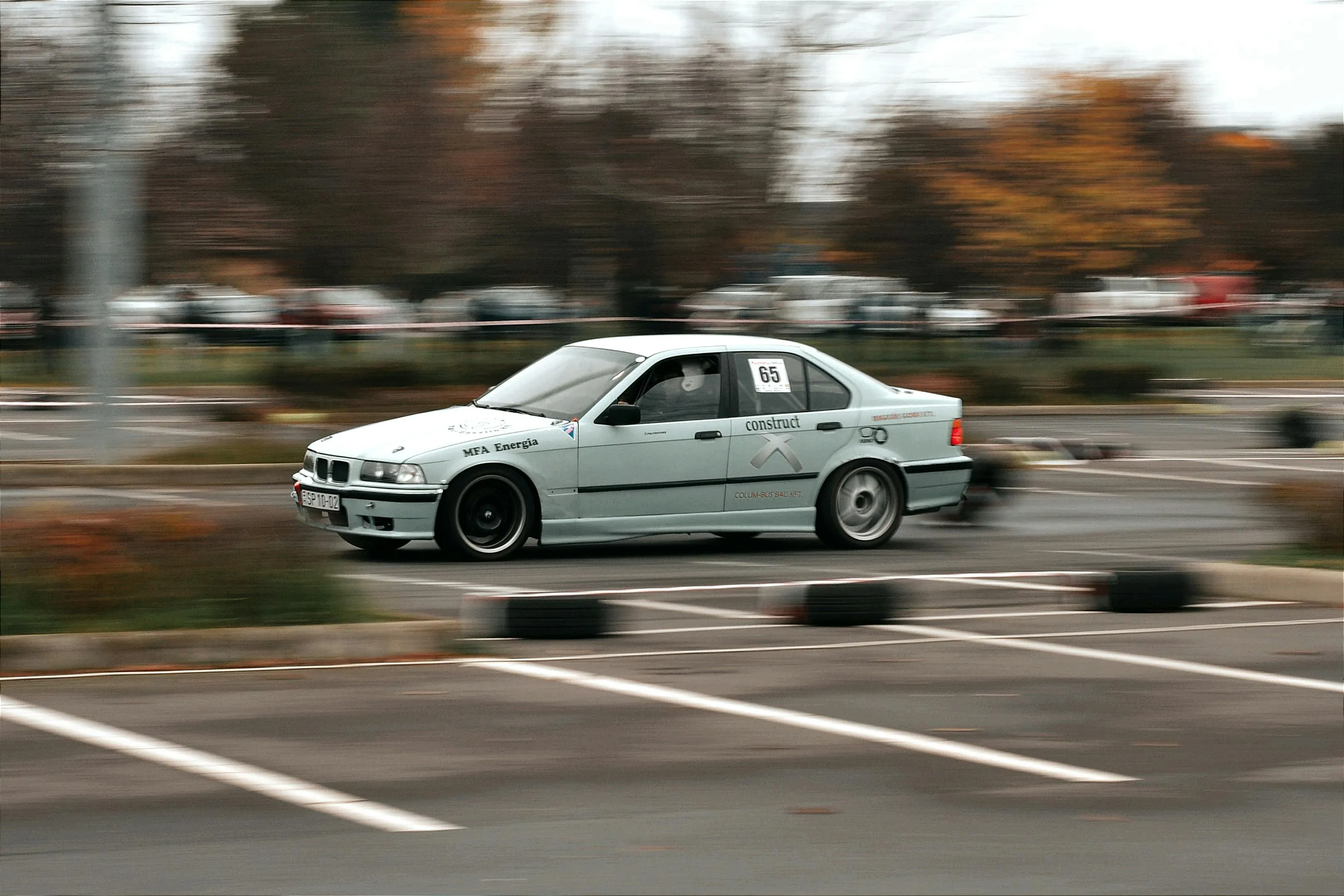 Classic Bmw Driving on a Tree Lined City Street Wallpaper