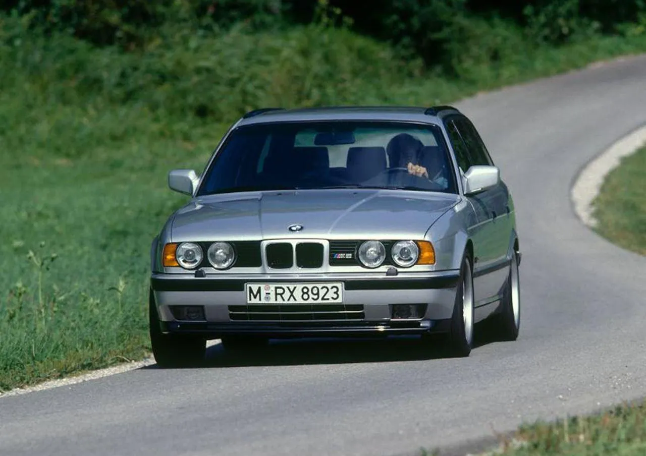 Classic Green Bmw Driving Along Winding Rural Road Image