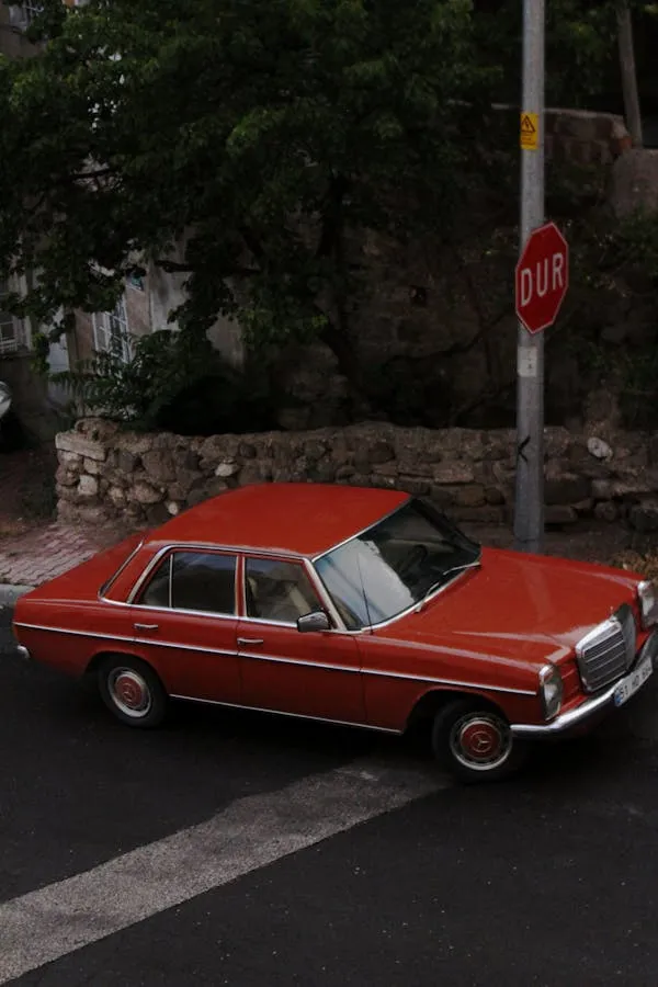 Classic orange Mercedes car parked near a stop sign