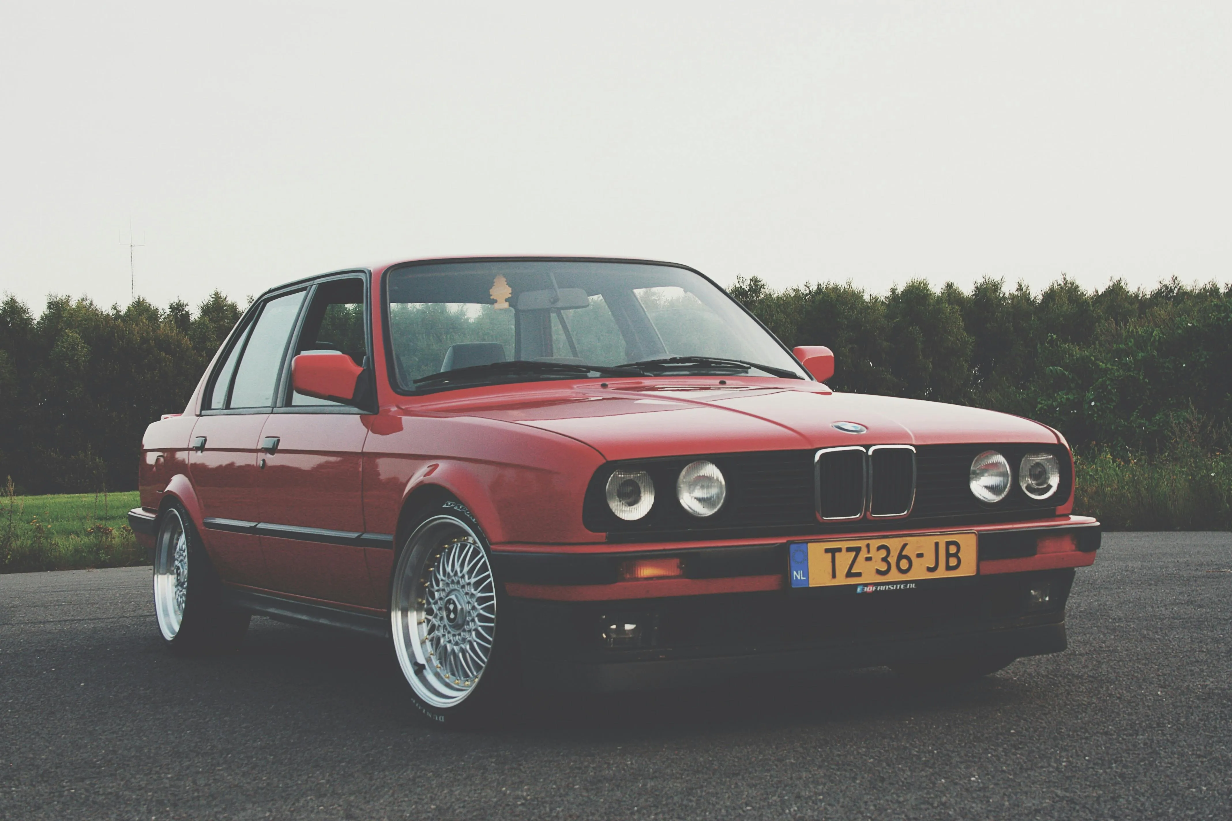 Classic Red Bmw Parked on Grass with Trees in the Background