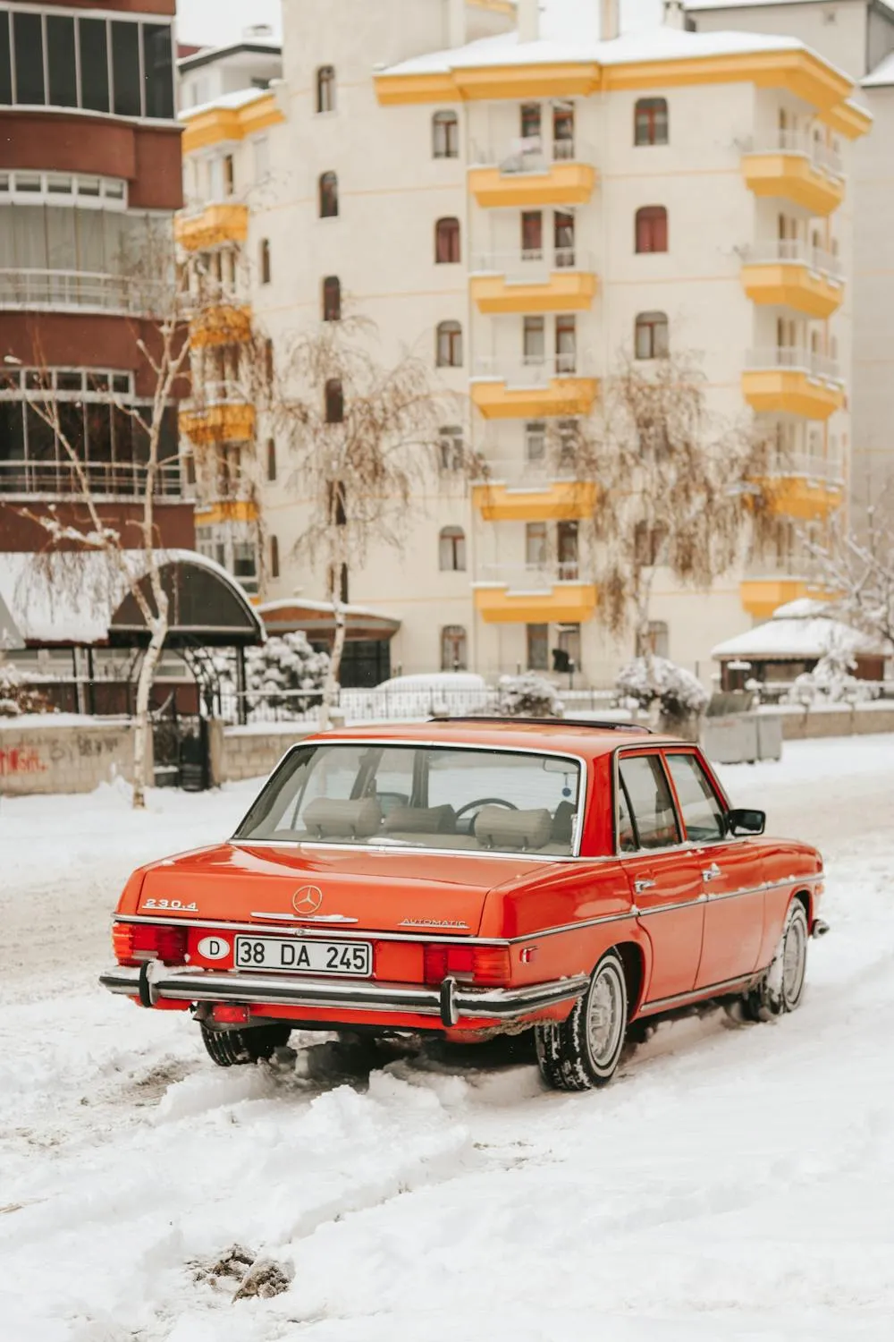 Classic Red Mercedes Driving Through Snowy Town image