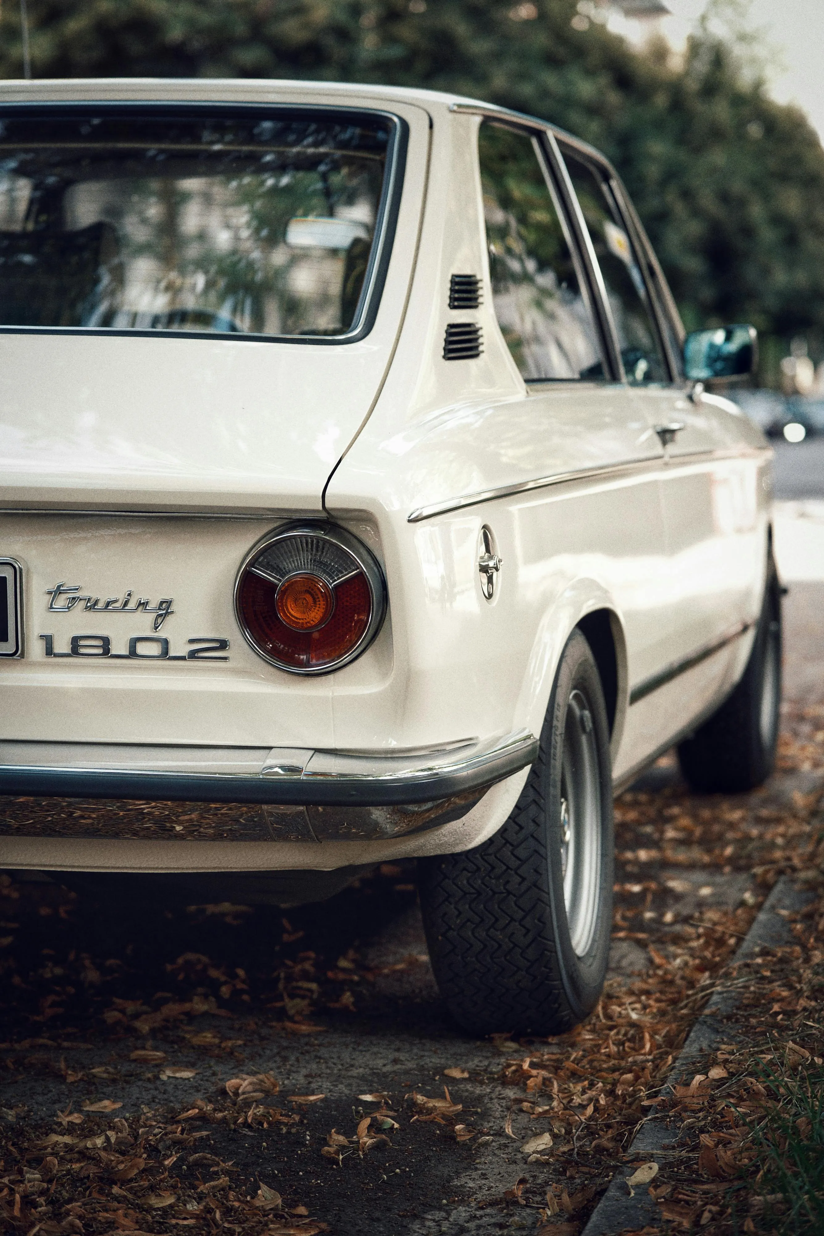 Classic White Bmw Car Parked Near Green Trees in Sunlight