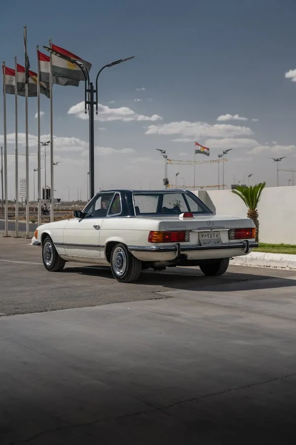 Classic White Mercedes Parked with Flags in Background