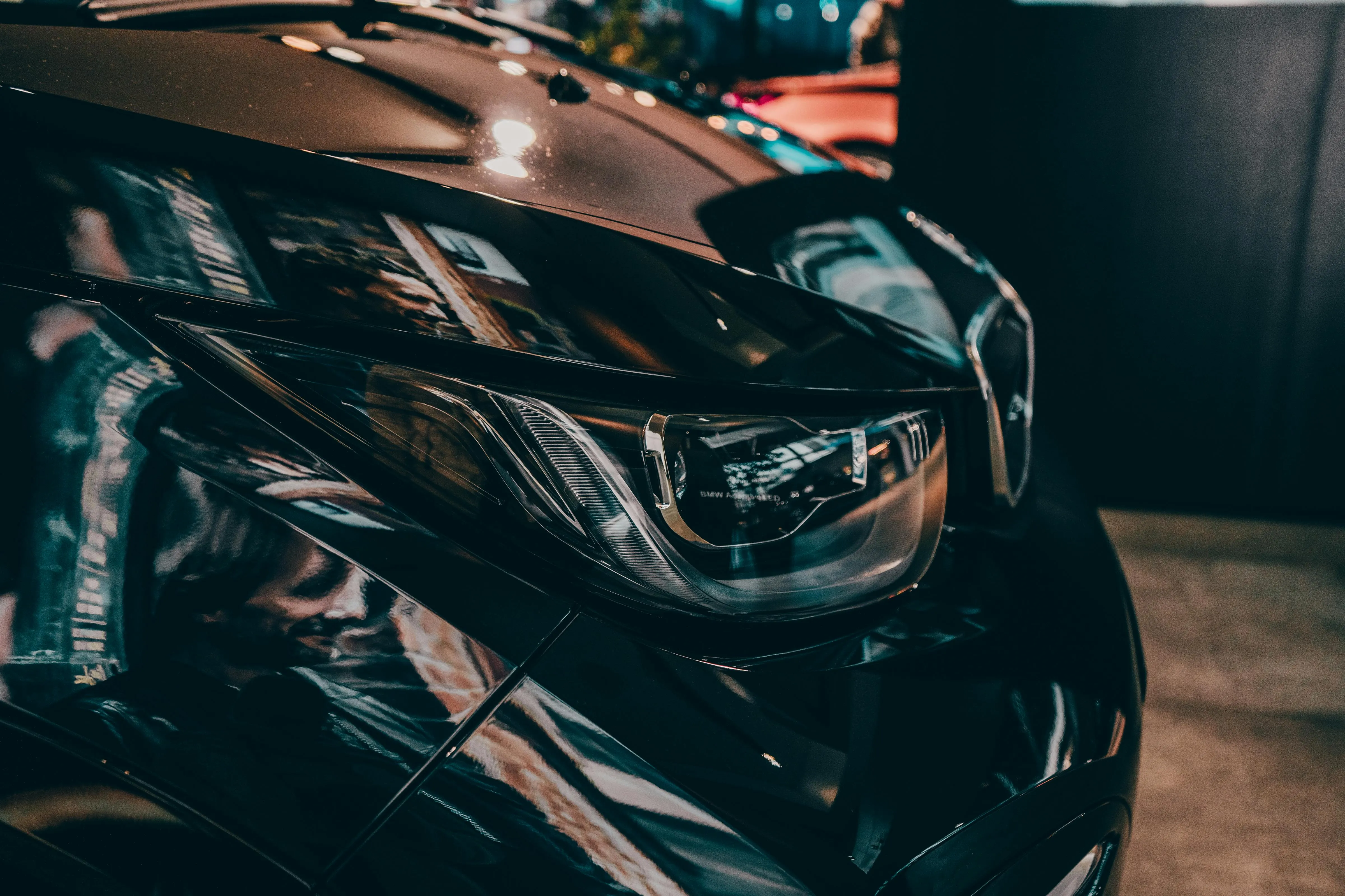 Closeup of a Black Bmw Headlight Under Warm Indoor Lights
