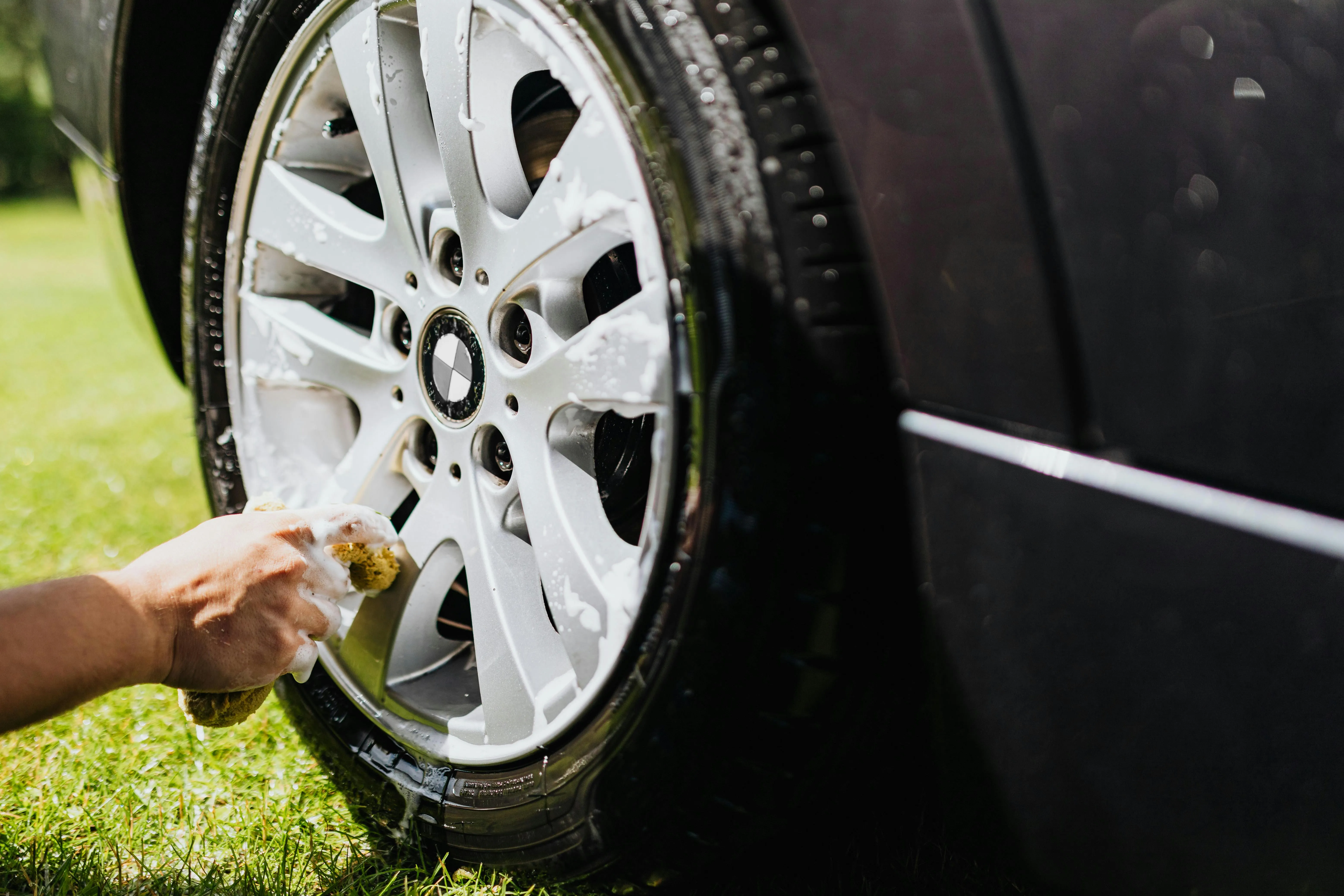 Closeup of Bmw Wheel Being Cleaned on Grassy Area Wallpaper