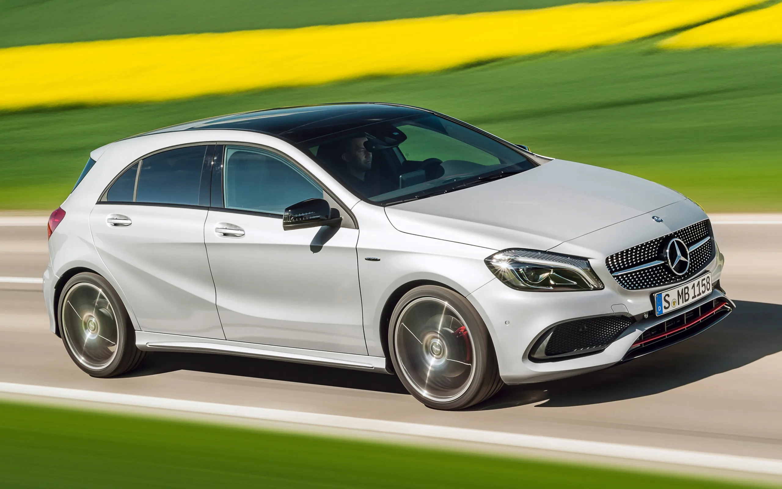Compact Mercedes Hatchback on Vibrant Country Road Wallpaper