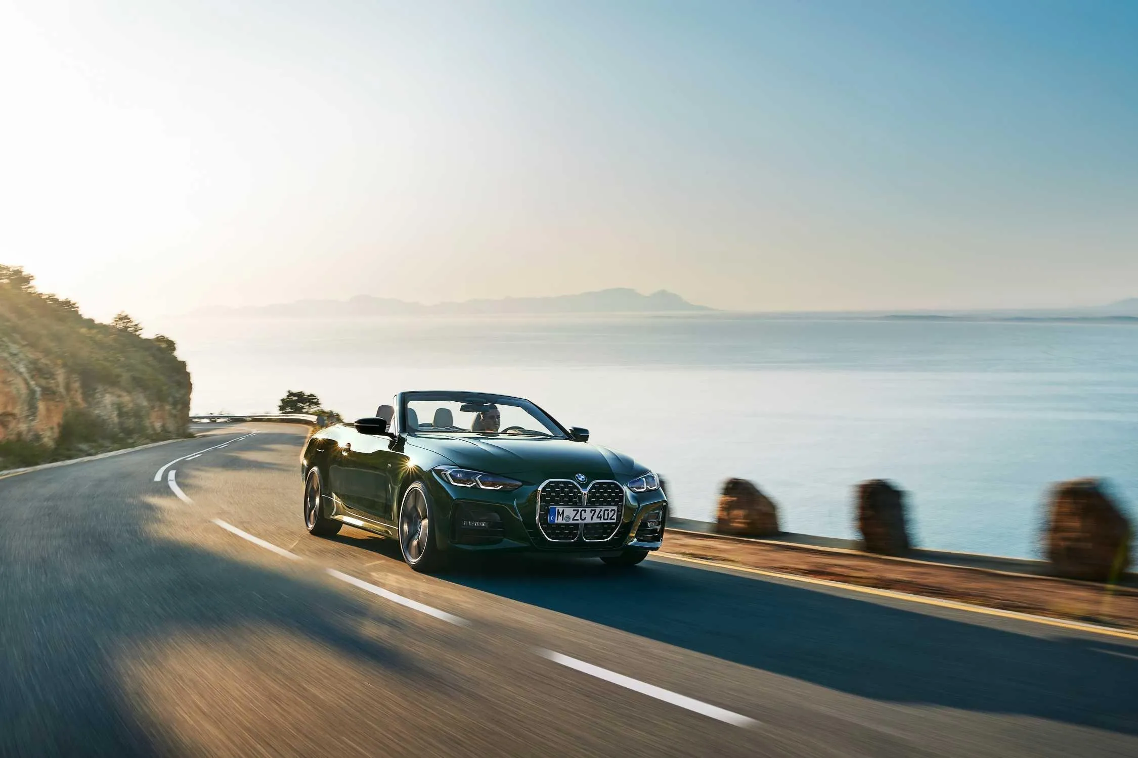 Convertible Bmw Driving Along Coastal Road at Sunset