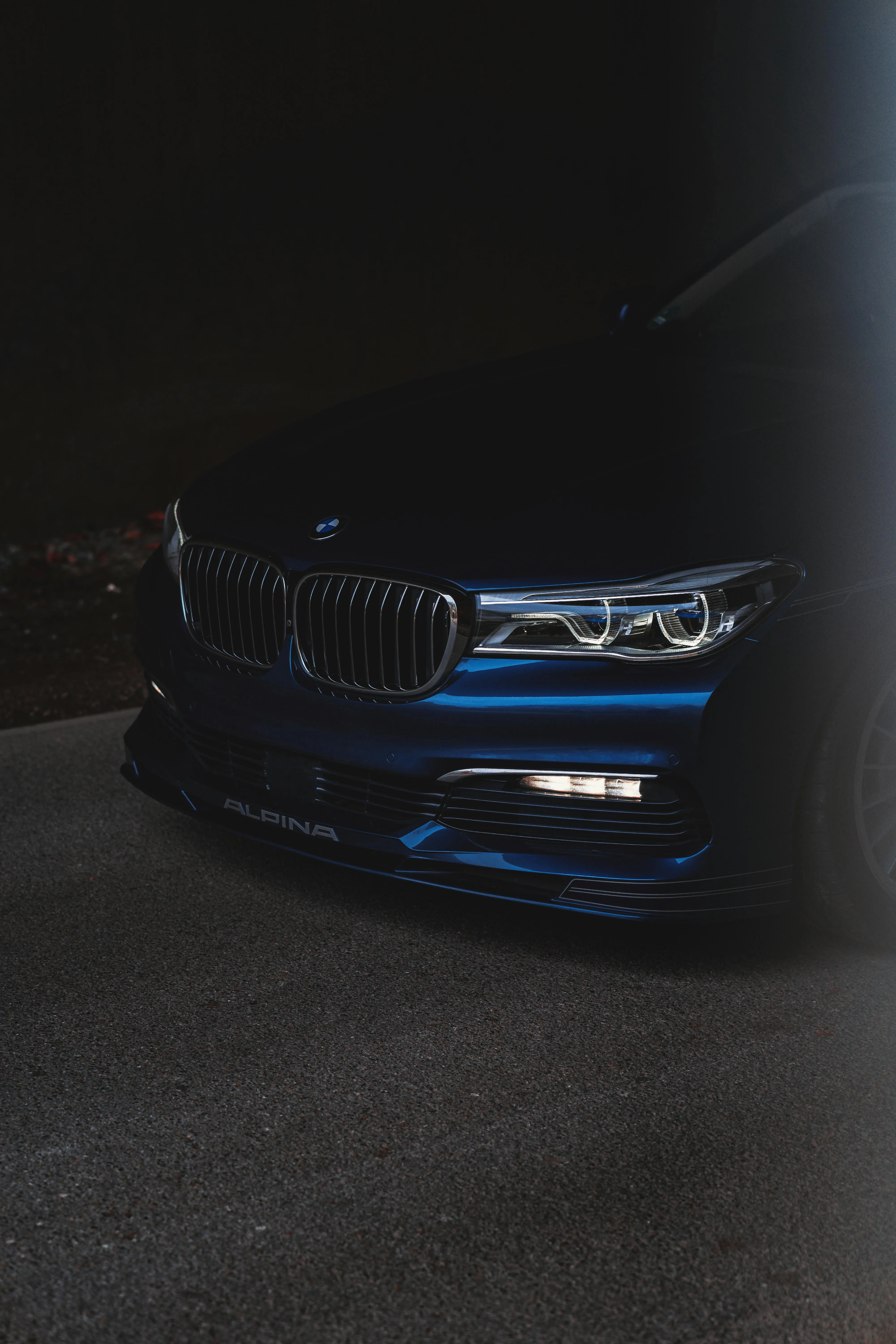 Dark Bmw Car with Headlights on in a Low Light Parking Area