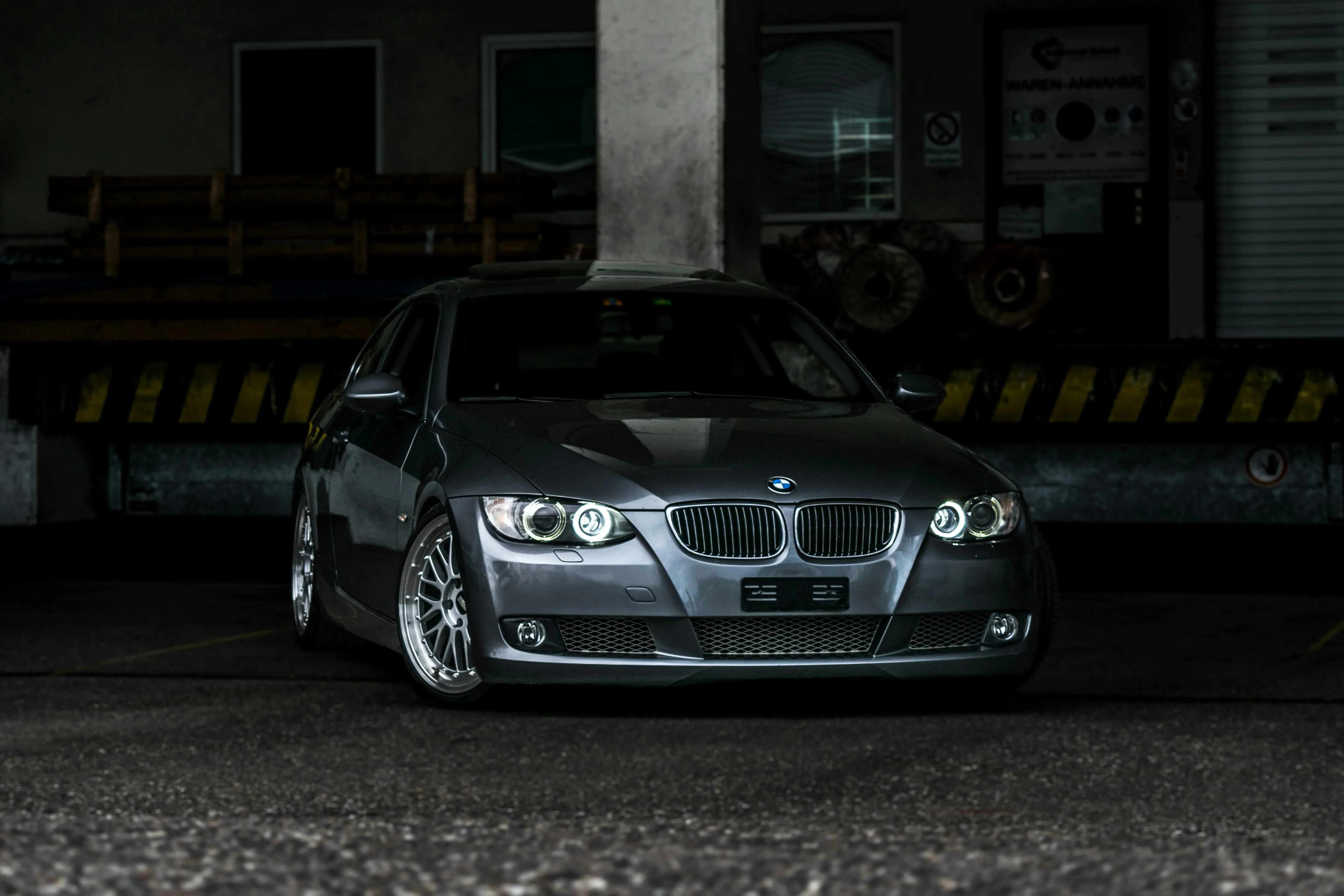 Dark Bmw Parked Under Building with Yellow Black Pillars