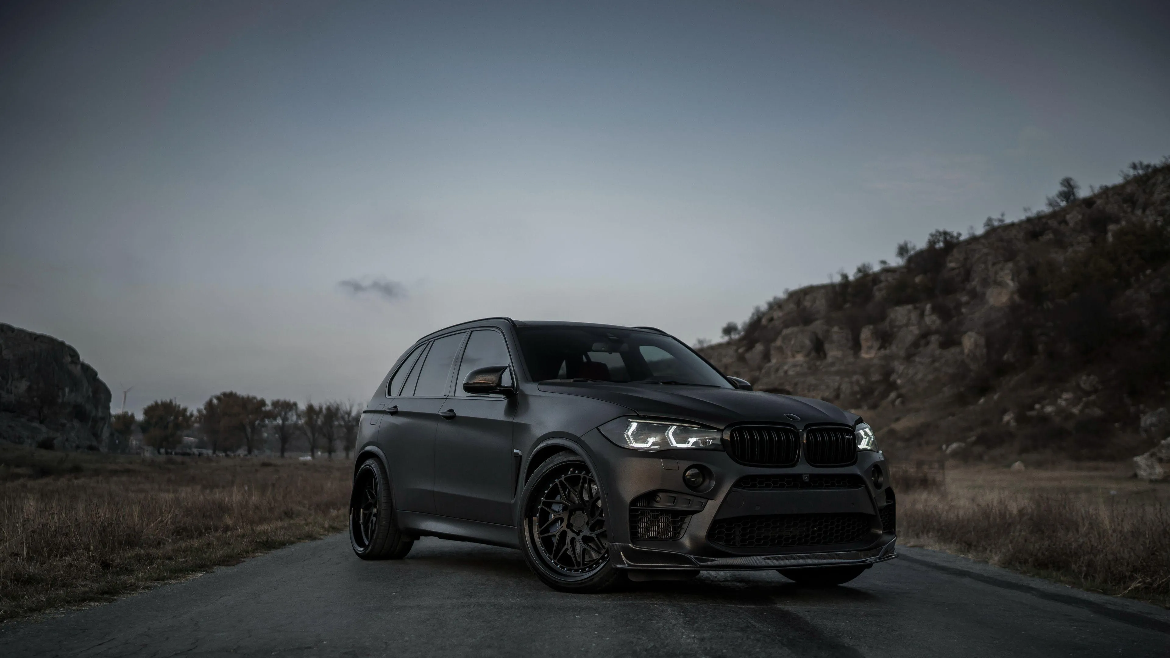 Dark Bmw Suv Parked on Empty Road Near Hill at Sunset