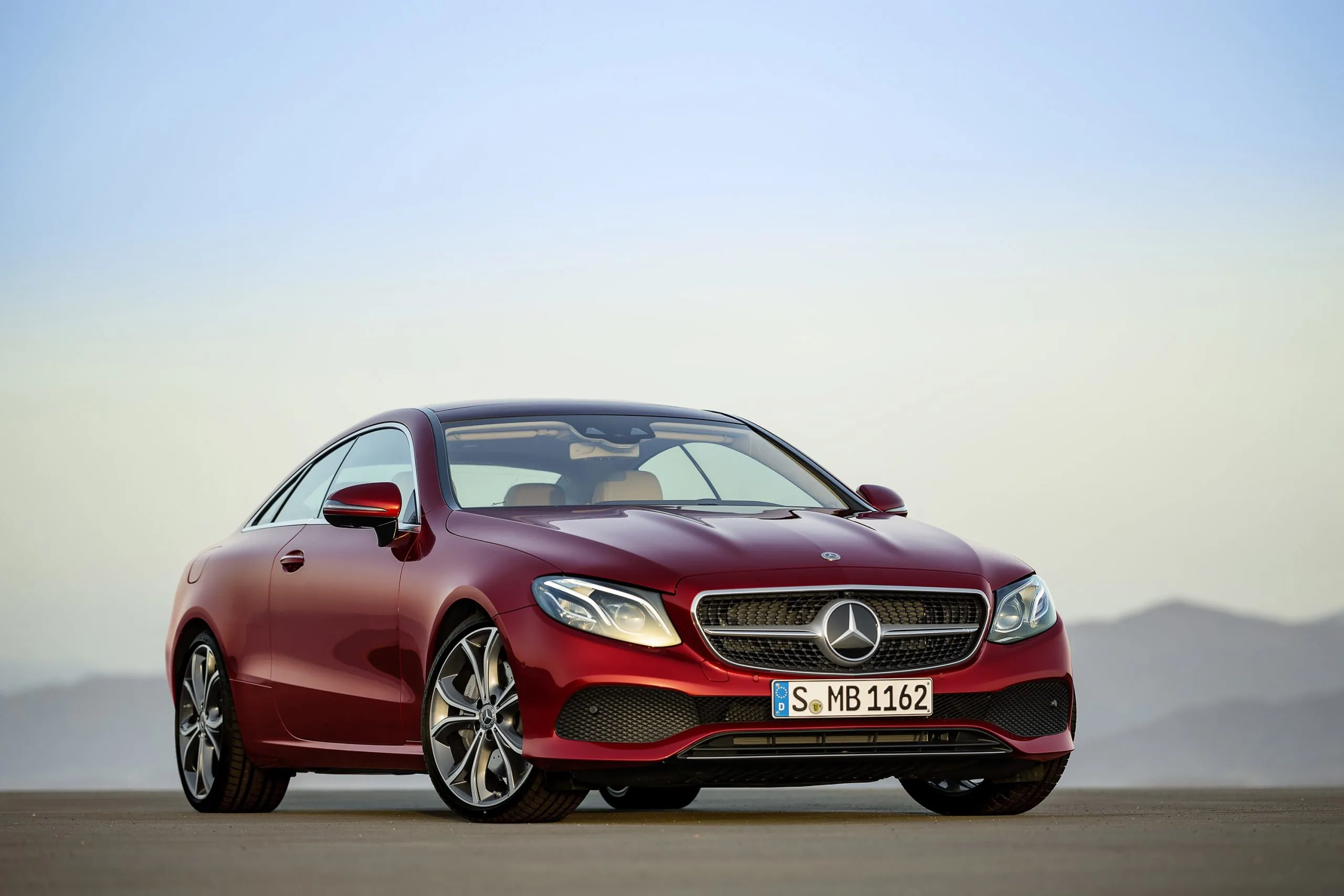 Elegant Red Mercedes Coupe on a Scenic Road Drive Wallpaper