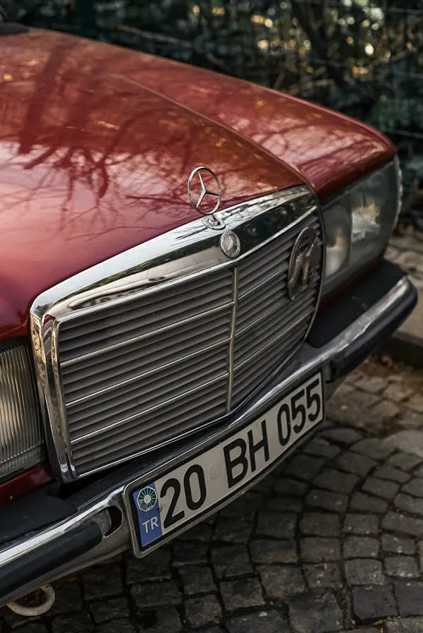 Front view of aged red Mercedes parked on cobblestone