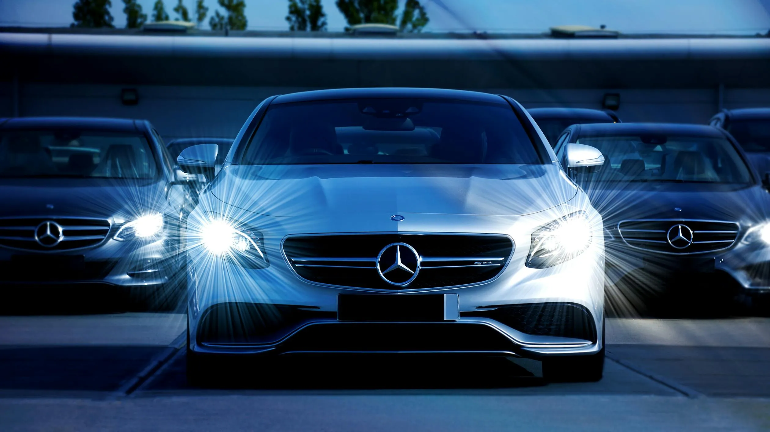 Front View of Mercedes Benz Cars with Headlights On in Dark