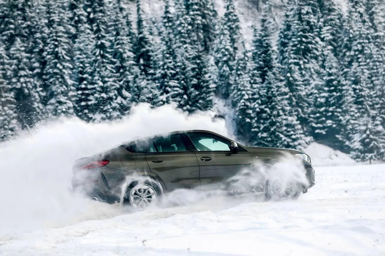 Green Bmw Car Drifting in Snow in Front of Snow Covered Trees