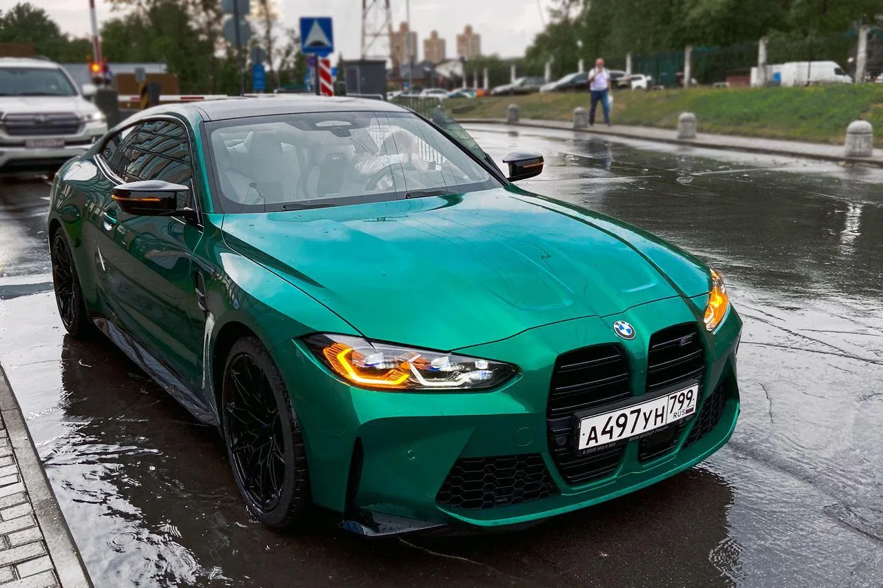 Green Bmw M3 Driving in Rainy City Street with Headlights On