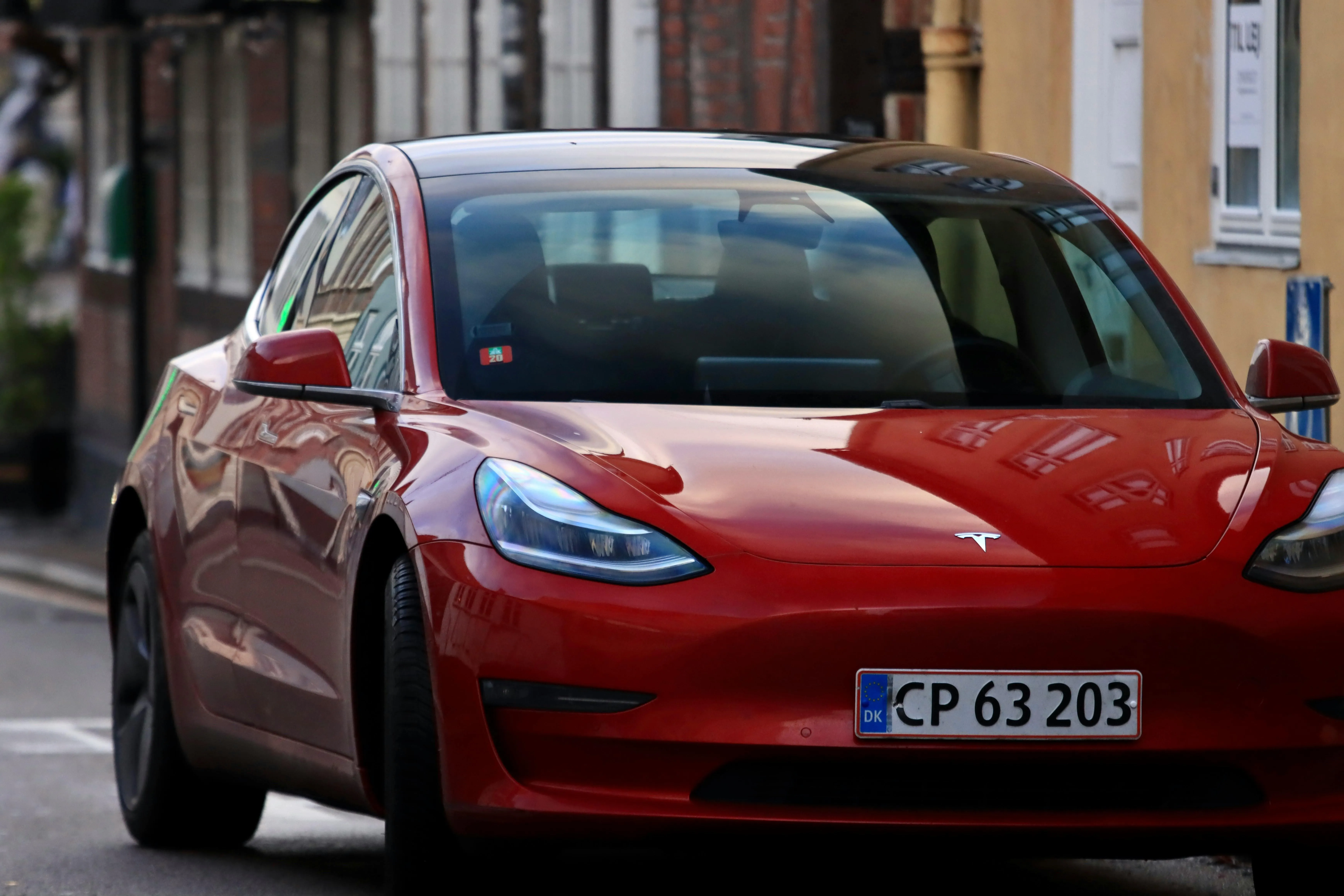 HD of Red Tesla Model 3 with European Plate on City Street