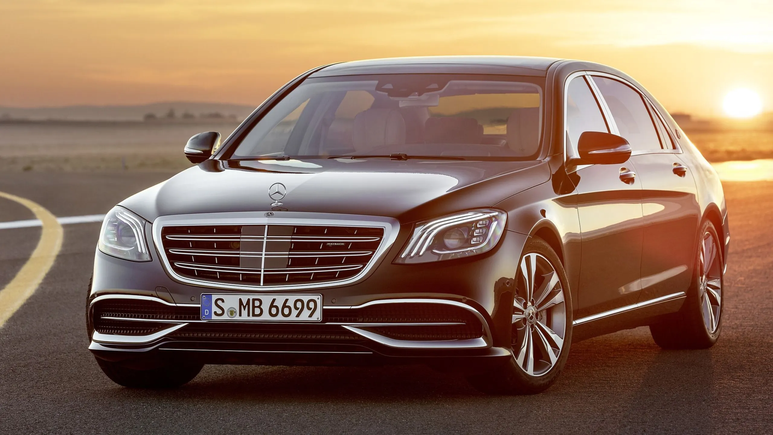 Luxury Black Mercedes Benz Sedan Driving at Sunset Wallpaper