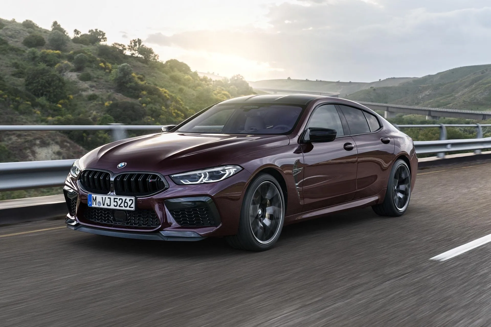 Maroon Bmw M8 Driving on Road in Mountain Landscape
