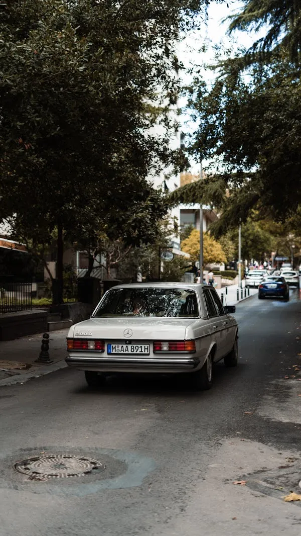 Mercedes Benz Driving Down Narrow City Street at Dusk