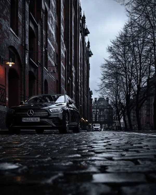 Mercedes Benz Sedan on Wet Cobblestone Street at Dusk