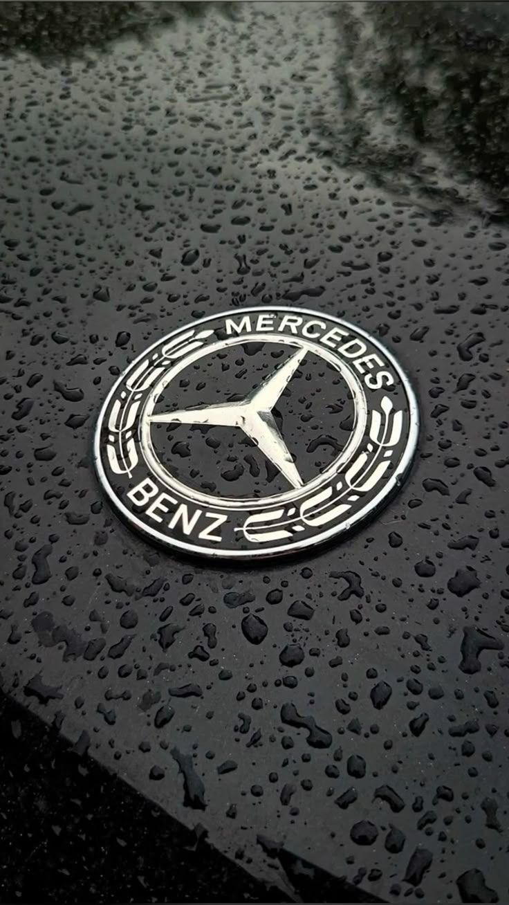 Mercedes Benz Star Emblem on Dark Wet Car Hood Surface