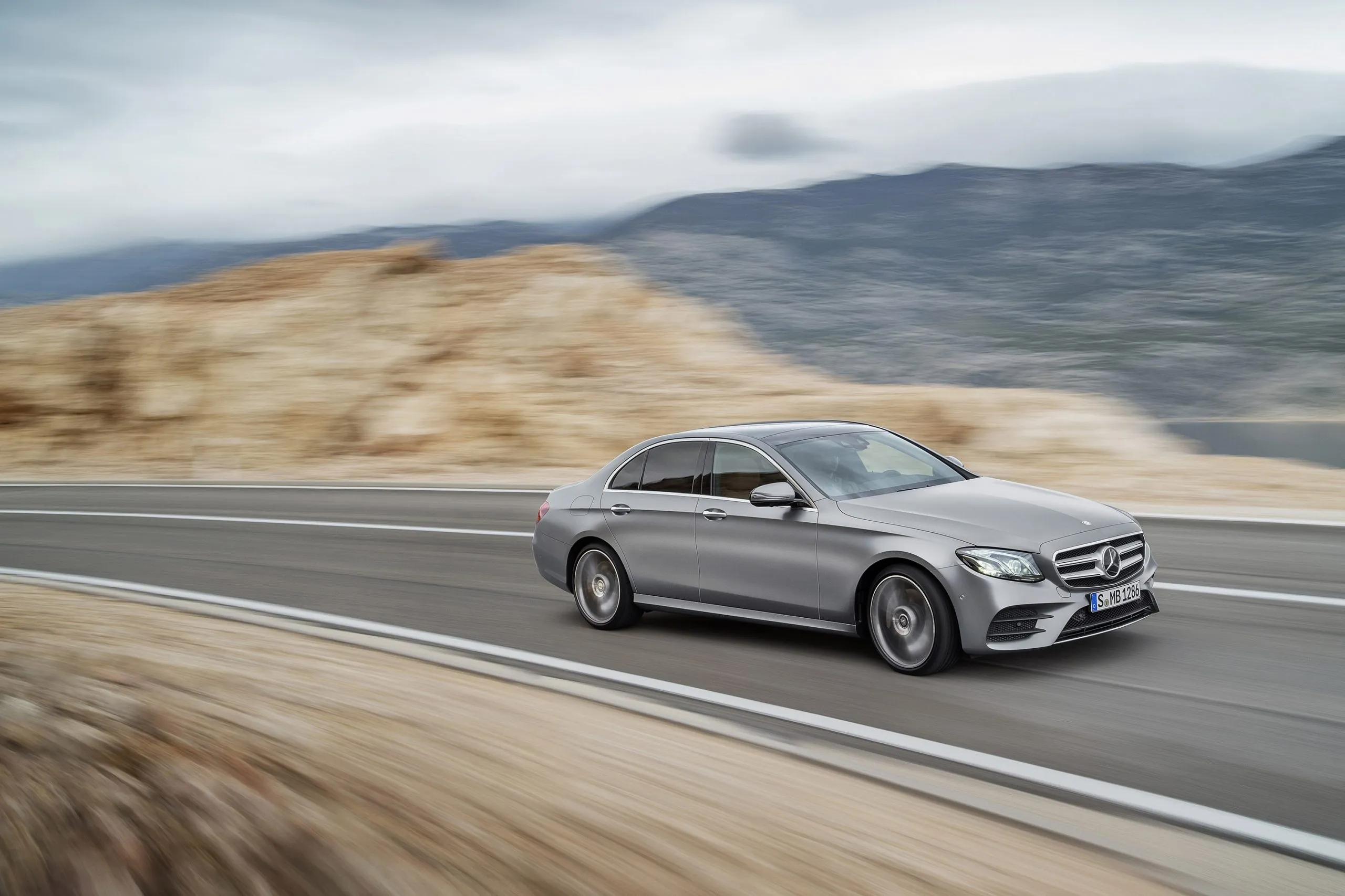 Mercedes Sedan Cruising Along Rocky Desert Road free HD image