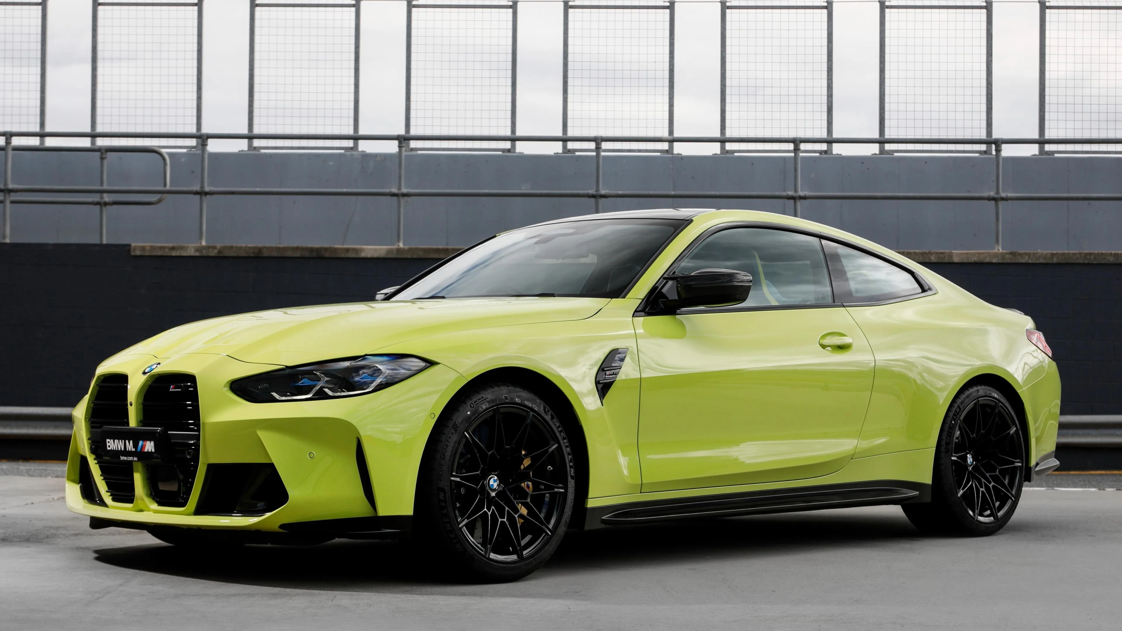 Neon Green Bmw Coupe Parked on Urban Street Under Fence