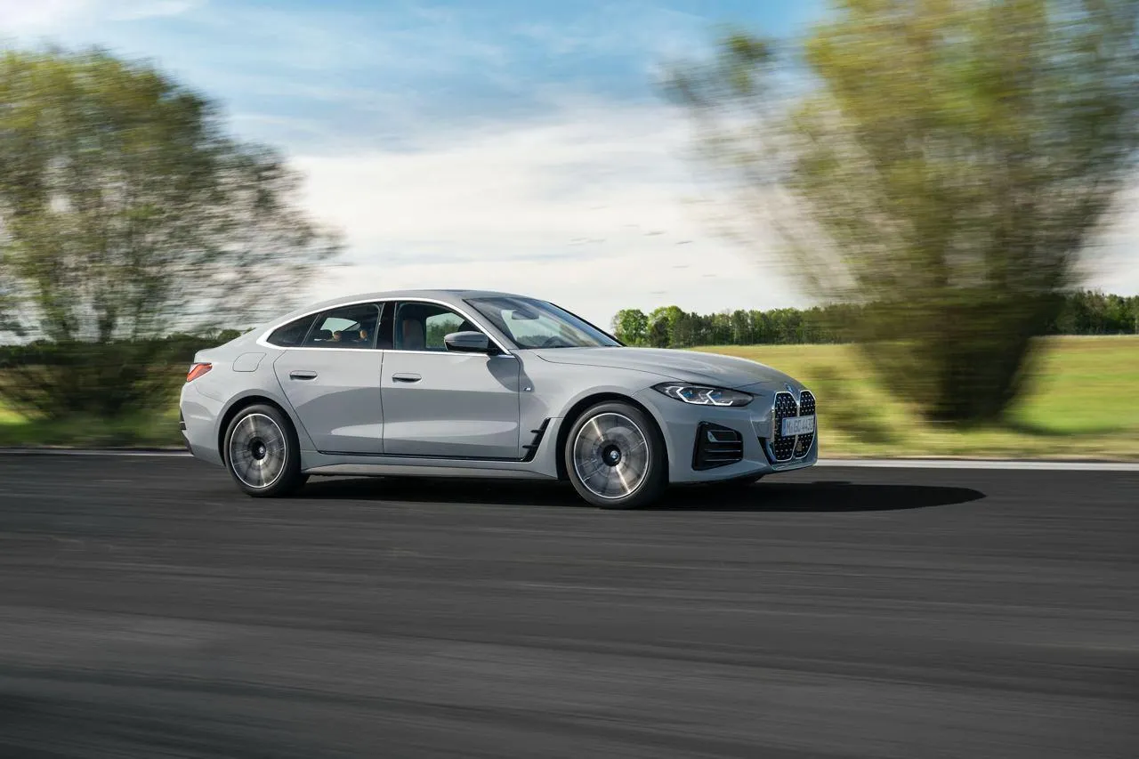 New Bmw Sedan Speeding Through Tree Lined Road Wallpaper
